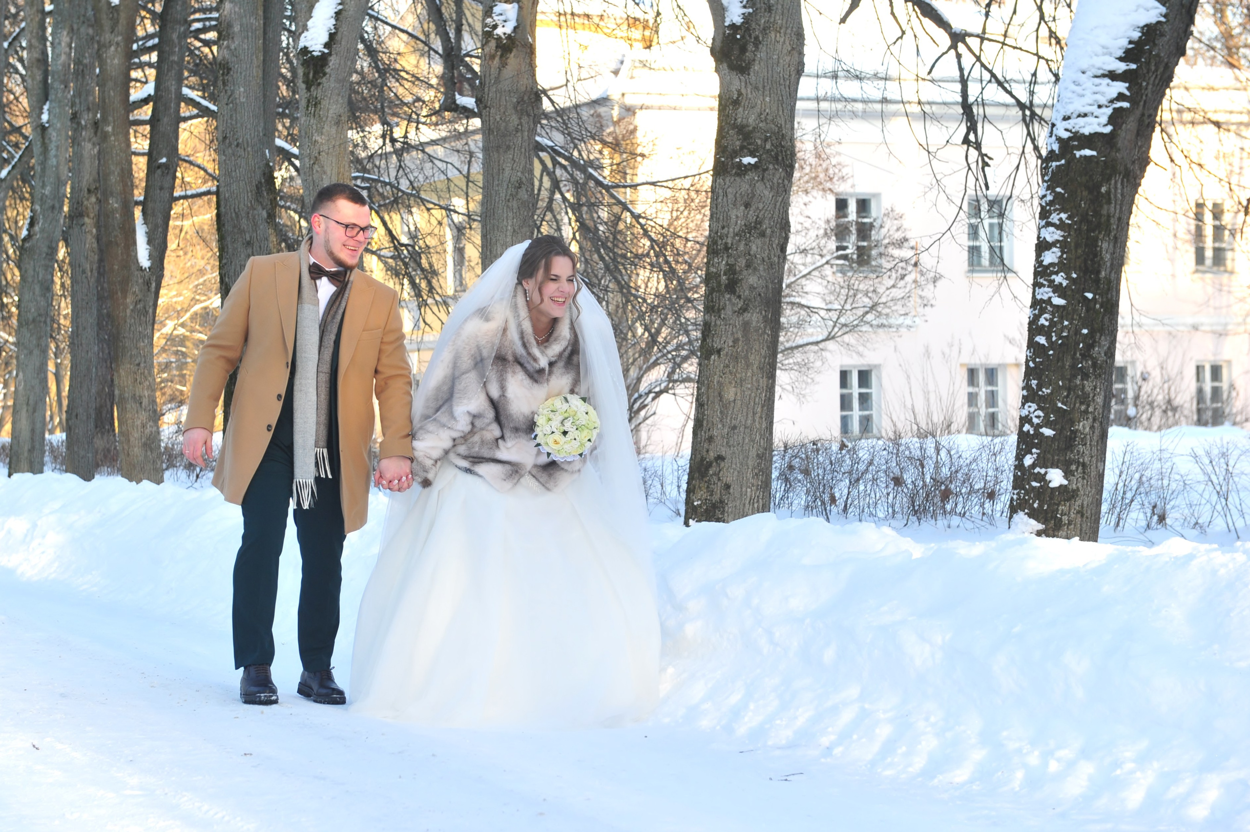 Зимняя свадьба в усадьбе Суханово, новобрачные идут по заснеженной дороге и держатся за руки