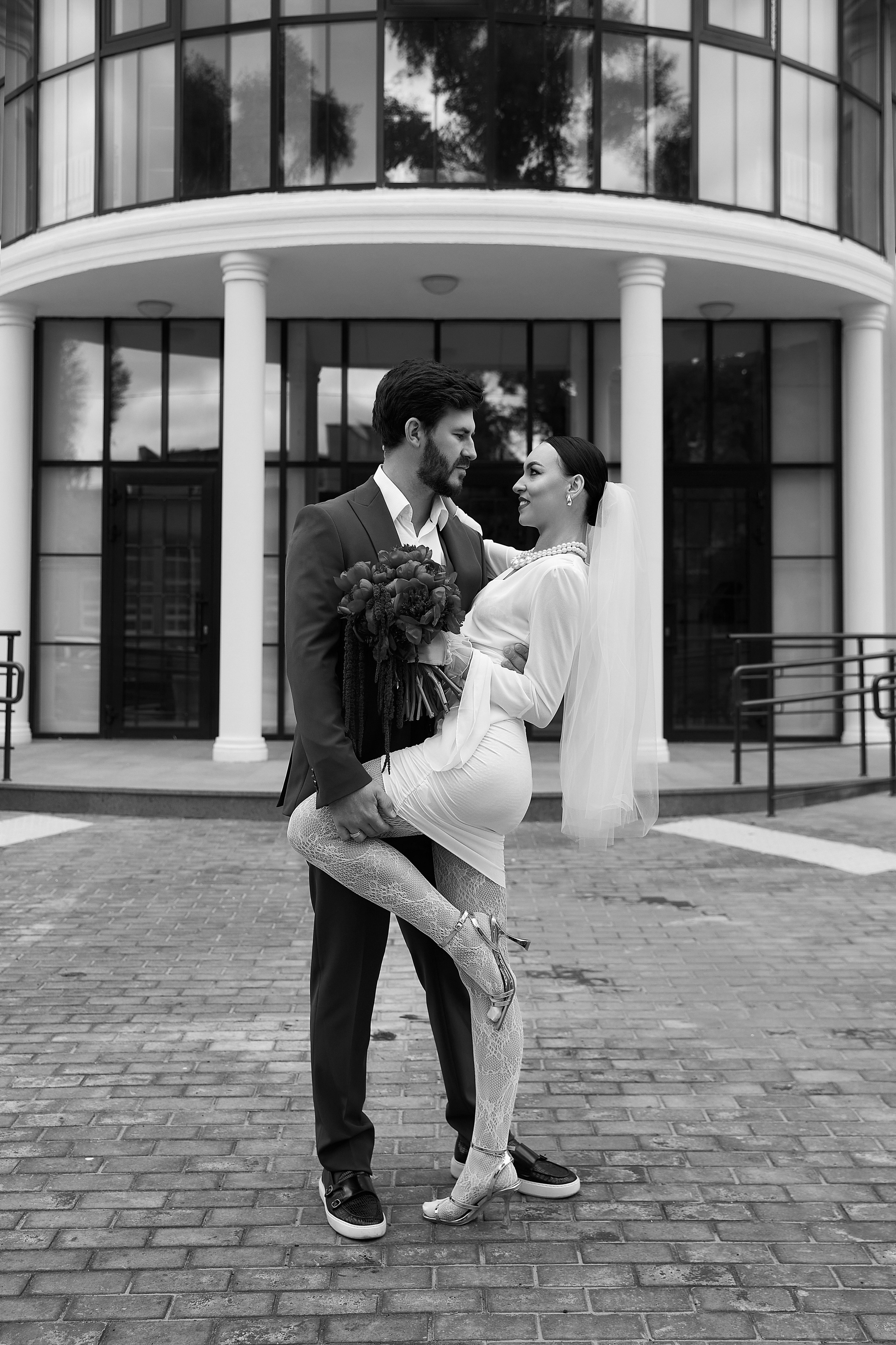 Свадебный фотограф Ульяновск: жених и невеста смотрят друг другу в глаза у театра. Эмоциональный портрет молодоженов. Елена Орешина. Парный портрет молодоженов в Казани: жених держит невесту на руках на фоне театральных колонн.Свадебная фотография в Норильске: жених и невеста в момент объятий на фоне архитектуры. Естественные эмоции от Елены Орешиной.