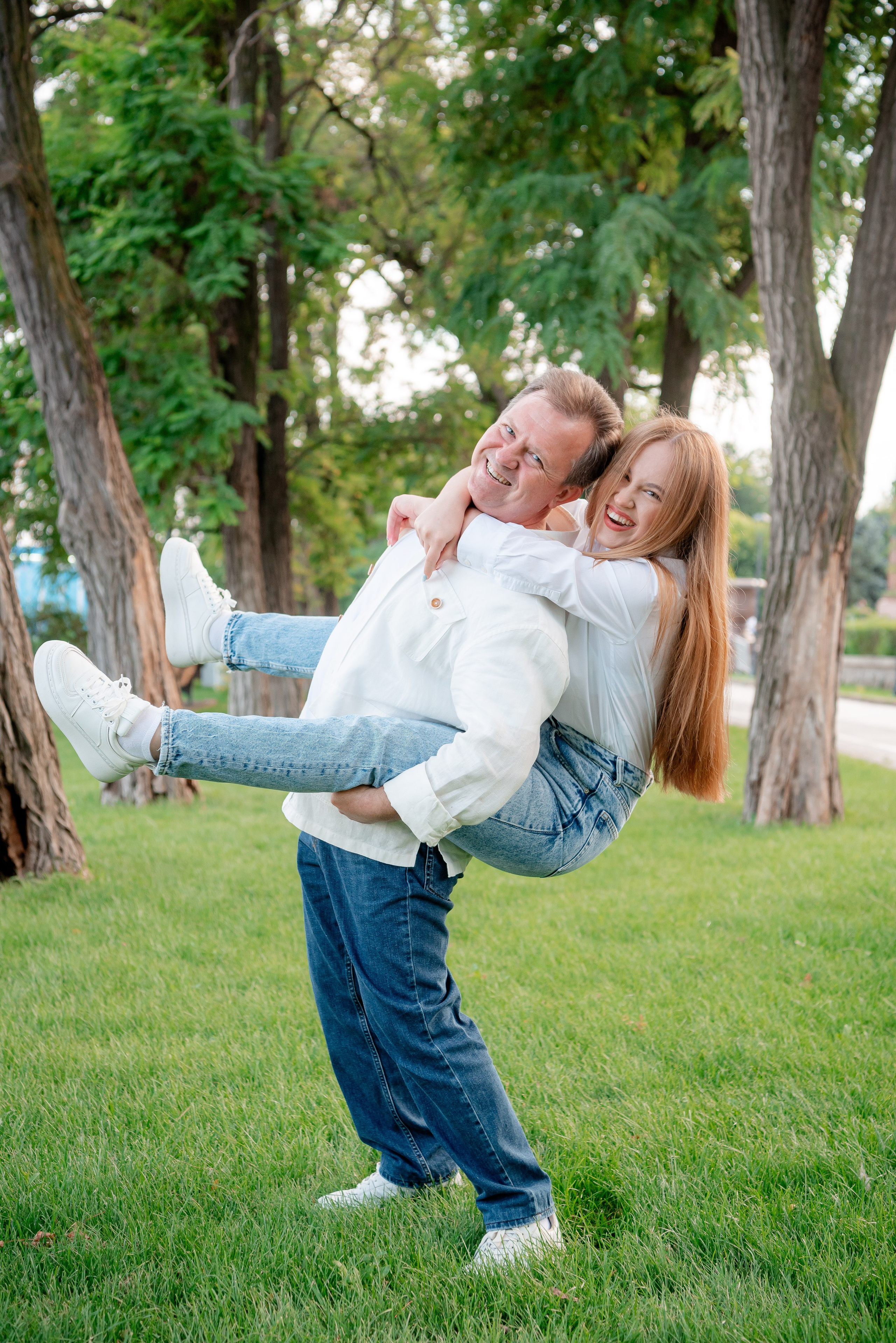 Взрослый папа катает на спине взрослую дочку в парке на набережной Волгограда