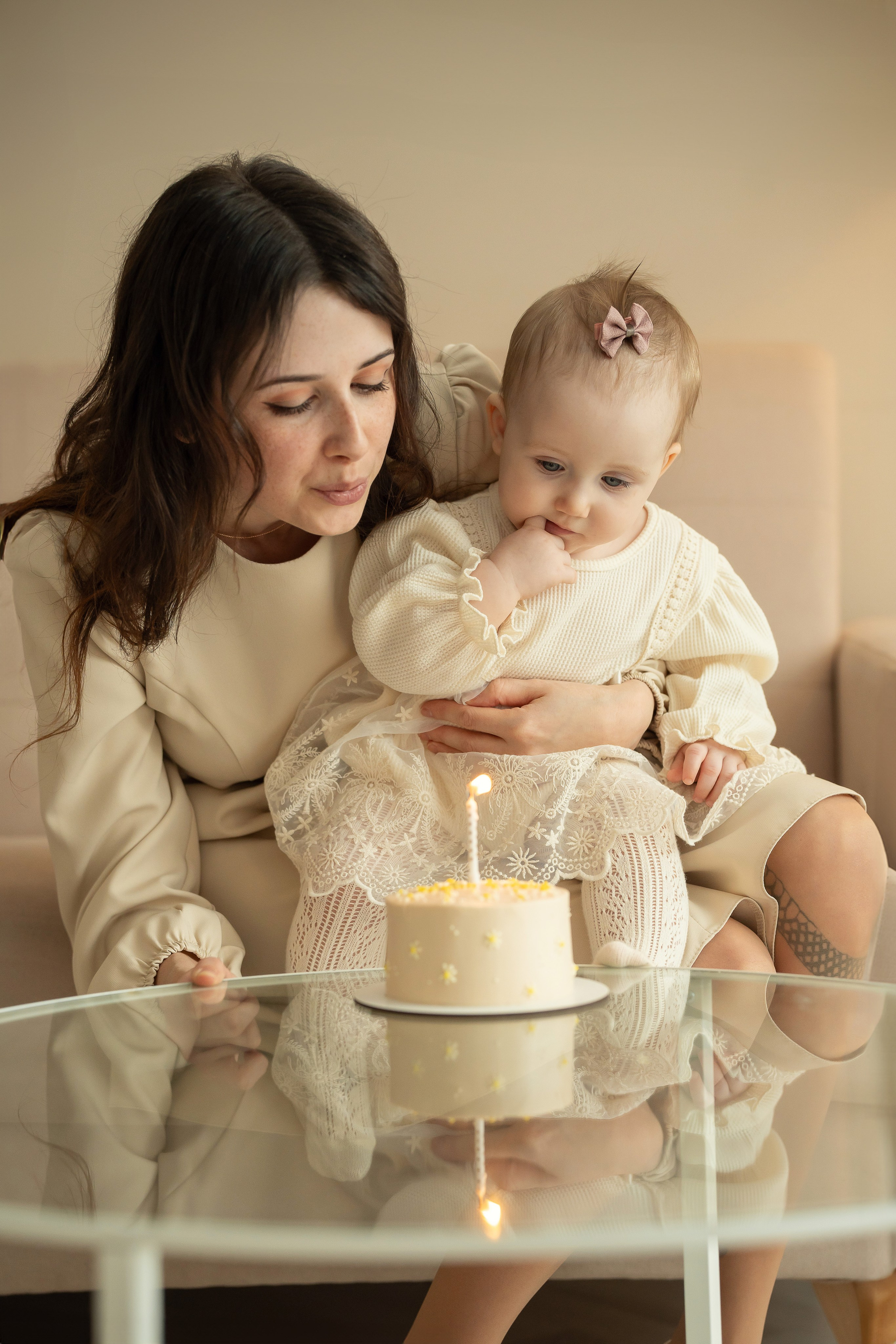 На фотосессии в студии мама с малышкой задувают свечку на тортике. Фотосессия на годовасию.