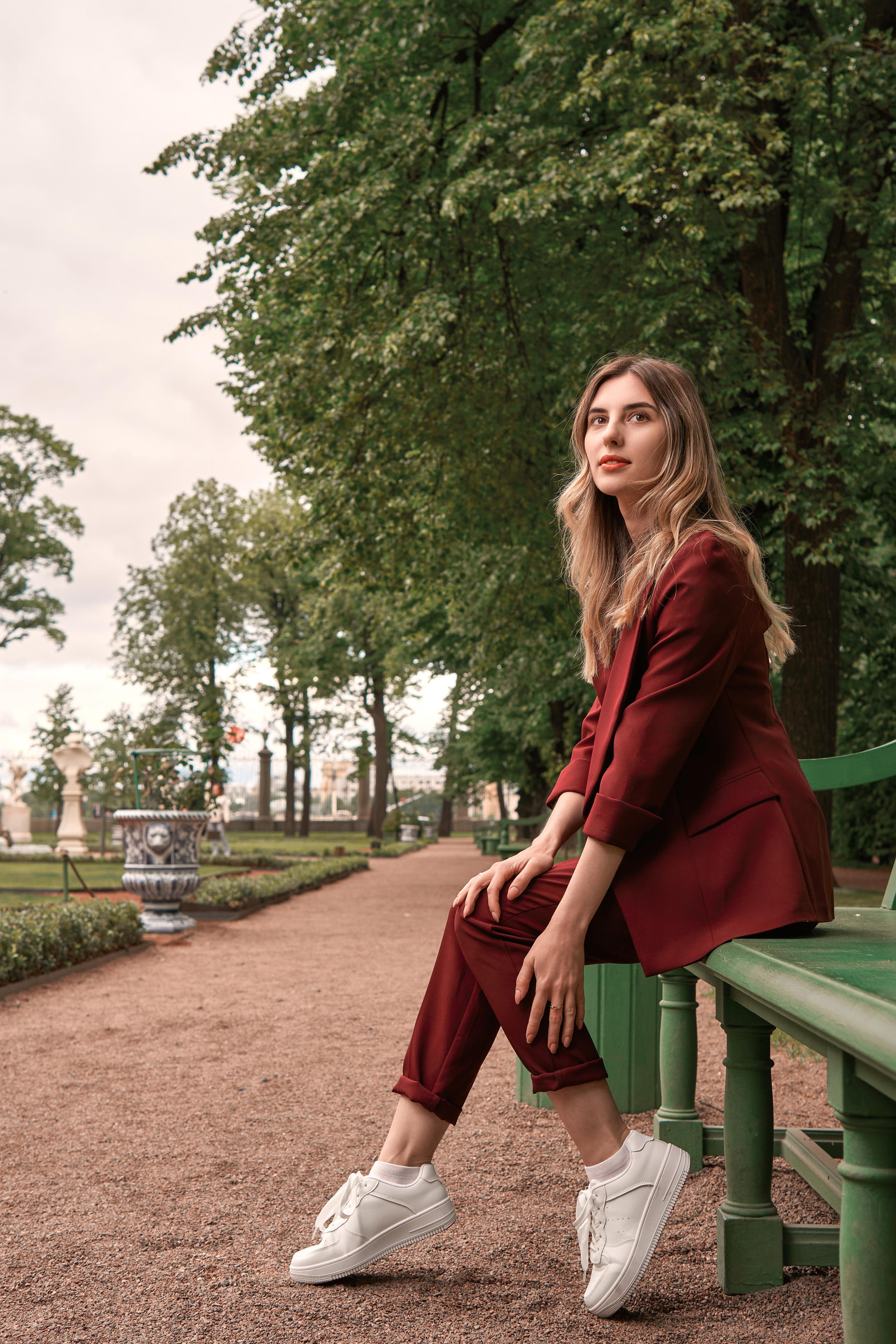 прогулочная фотосессия девушки в бордовом костюме в летнем саду со вспышкой летом в зелени в Санкт-Петербурге в стиле кино, стробизм днем в пасмурную погоду