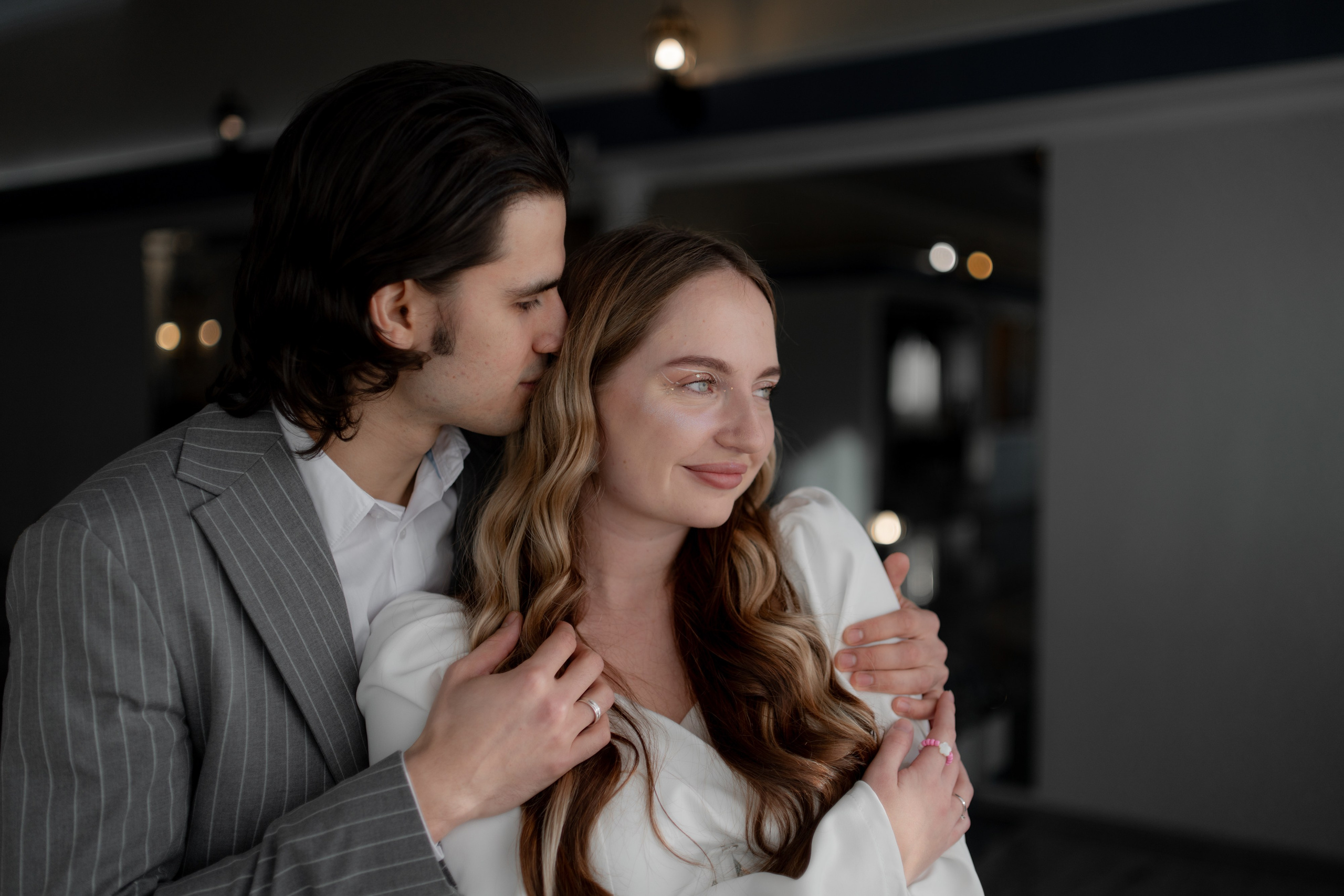 Свадебная пара обнимается в загсе Невского района на Октябрьской набережной обнимаются в лучах солнца в Санкт-Петербурге