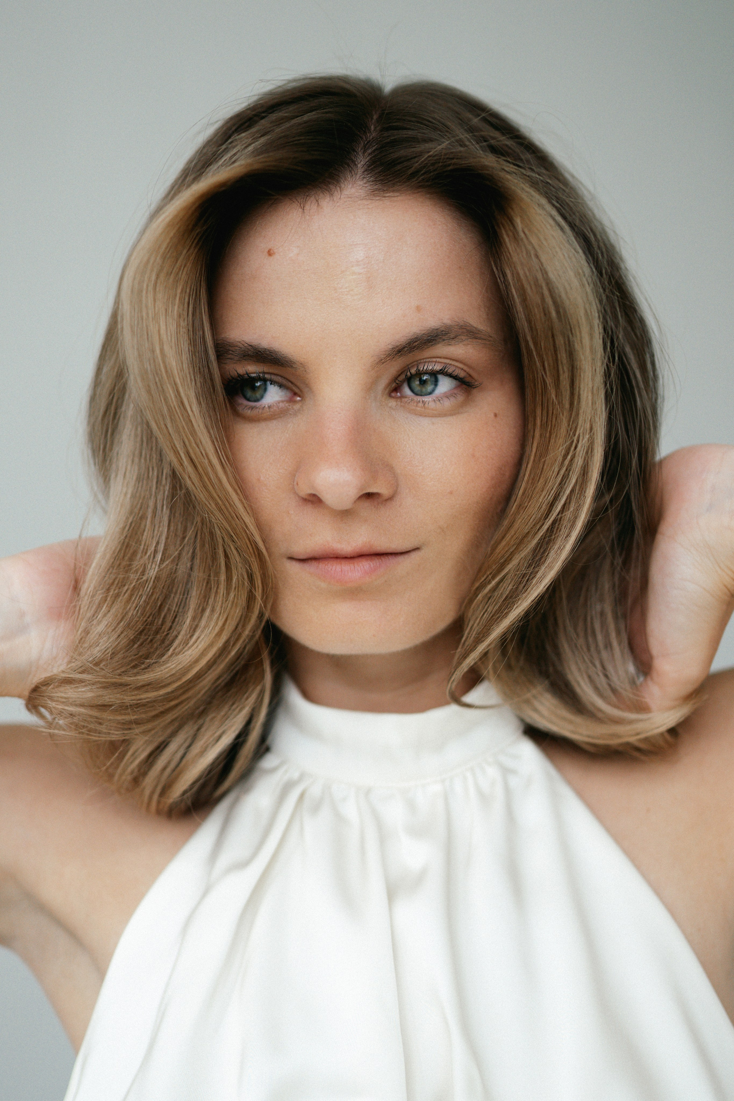 Портрет модели в белом платье Lichi на светлом фоне в студии Санкт-Петербурга