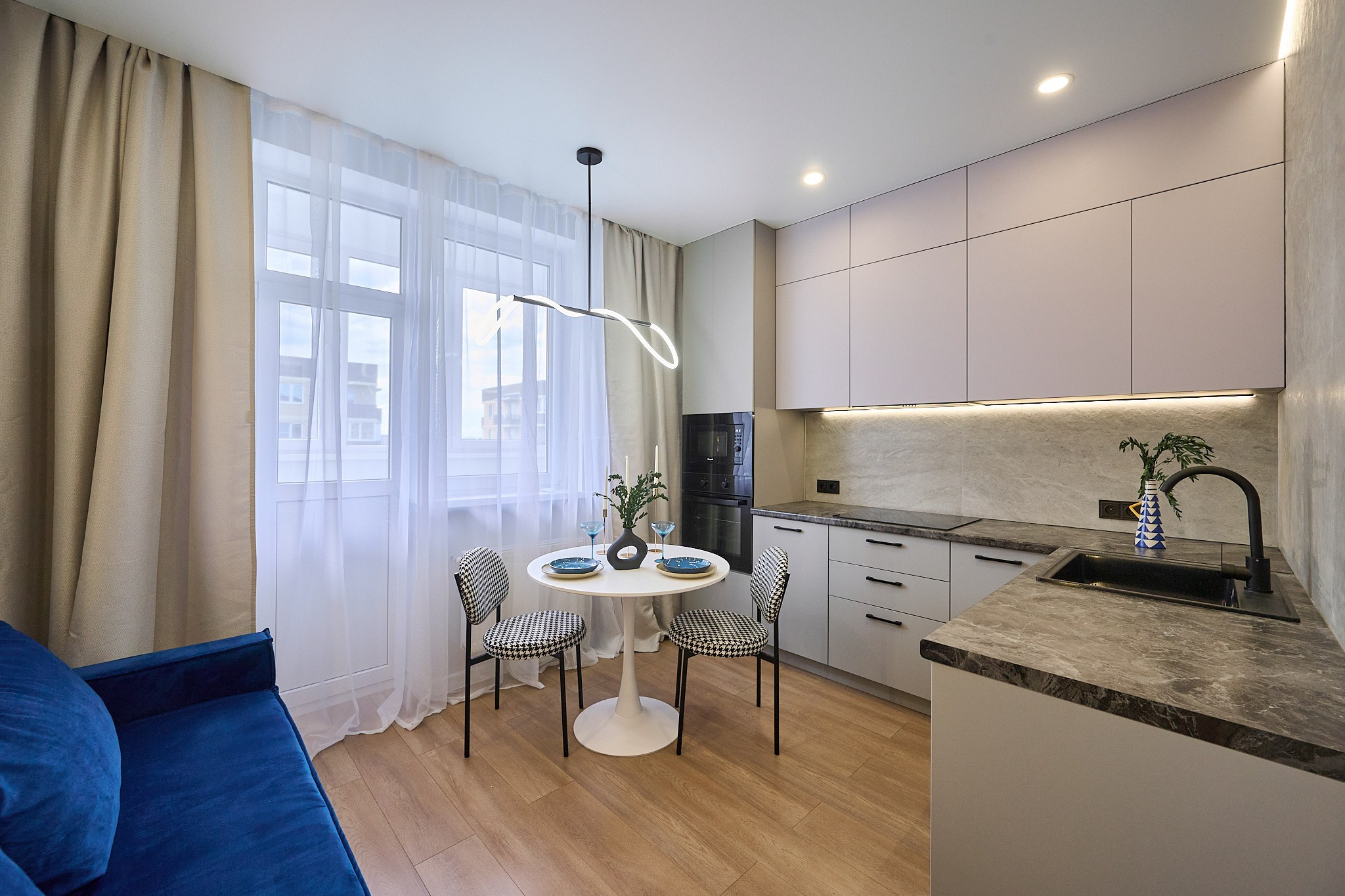 кухня в белых оттенках и синим диваном бежевыми шторами белые шкафы белый стол 