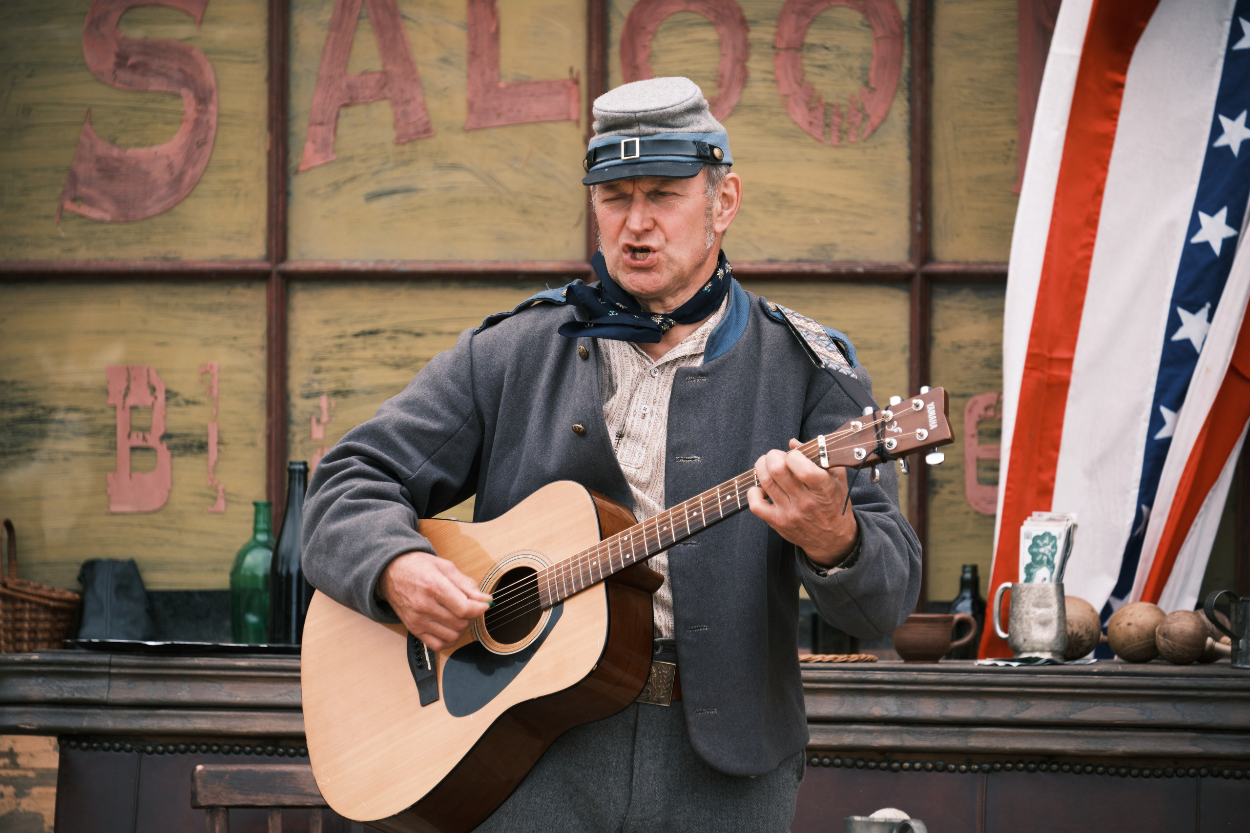 Мужчина играет на гитаре возле салона в ковбойском городке
