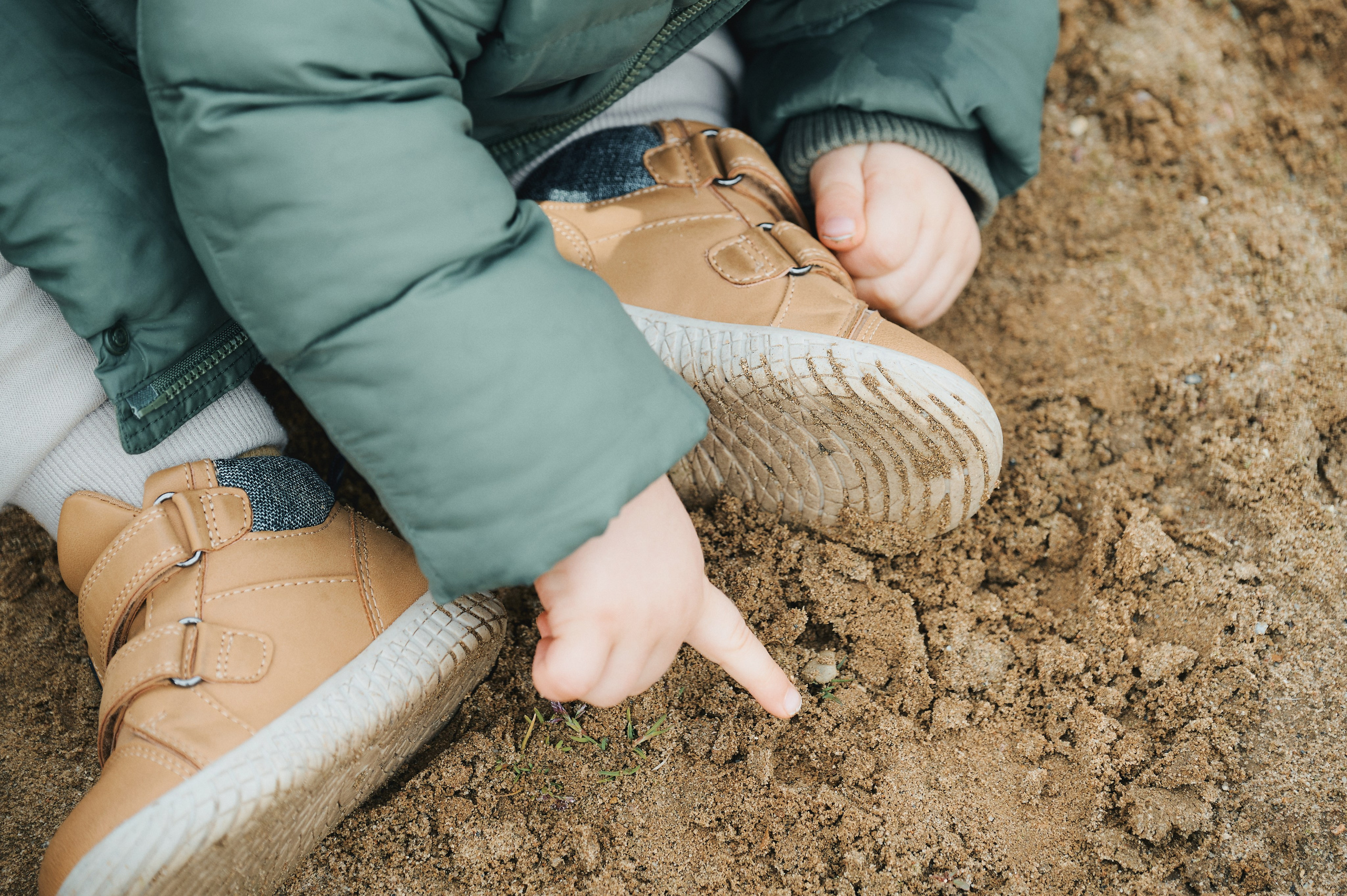 крупный план рук и ботинок ребёнка, играющего в песке
