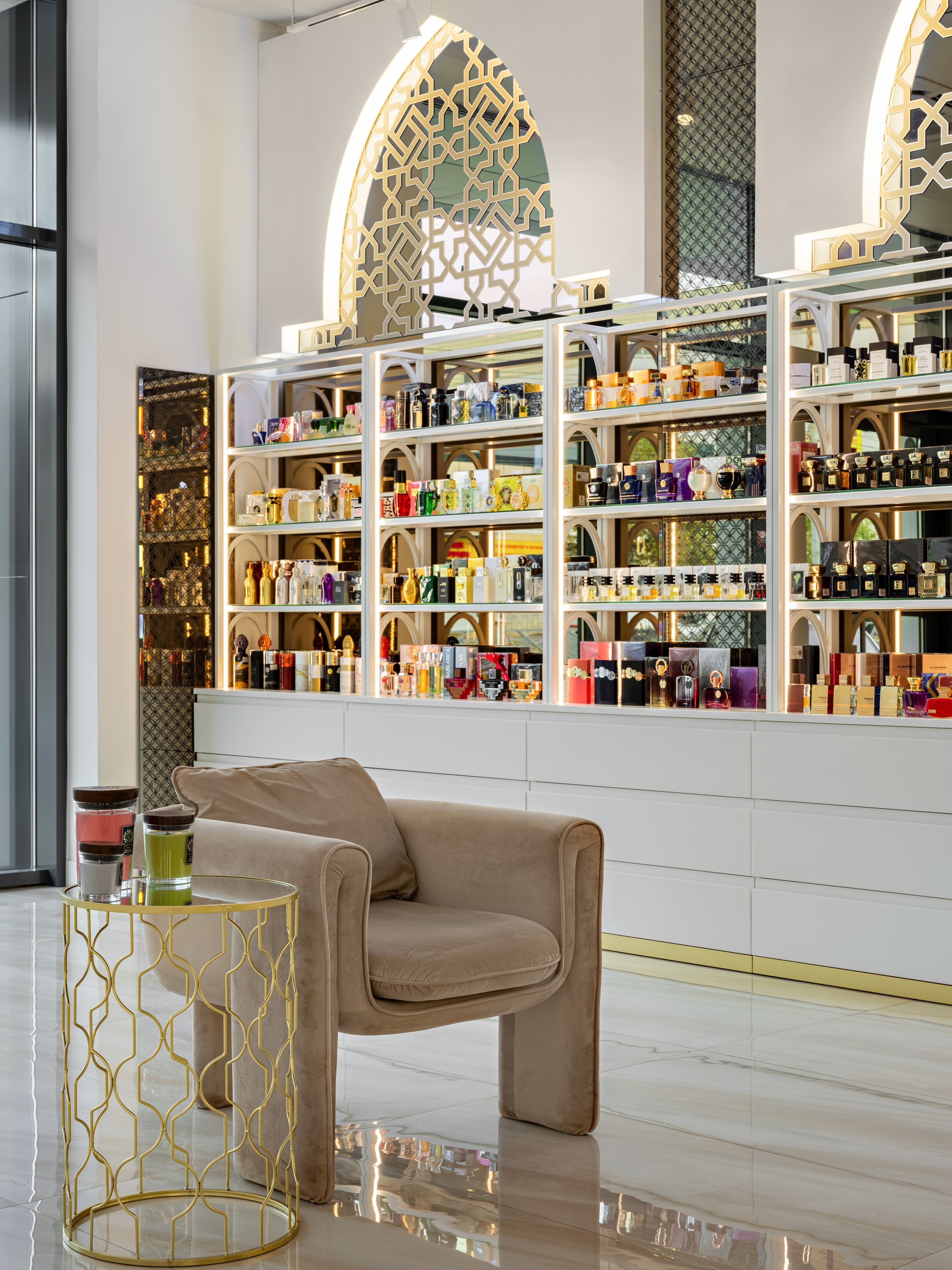 Элитный парфюмерный магазин с восточными арками, стеклянными полками и витринами, наполненными ароматами. Мягкое кресло и золотой столик на фоне мраморного пола, дизайнер Мария Никишина, фотограф Сергей Денисенко.