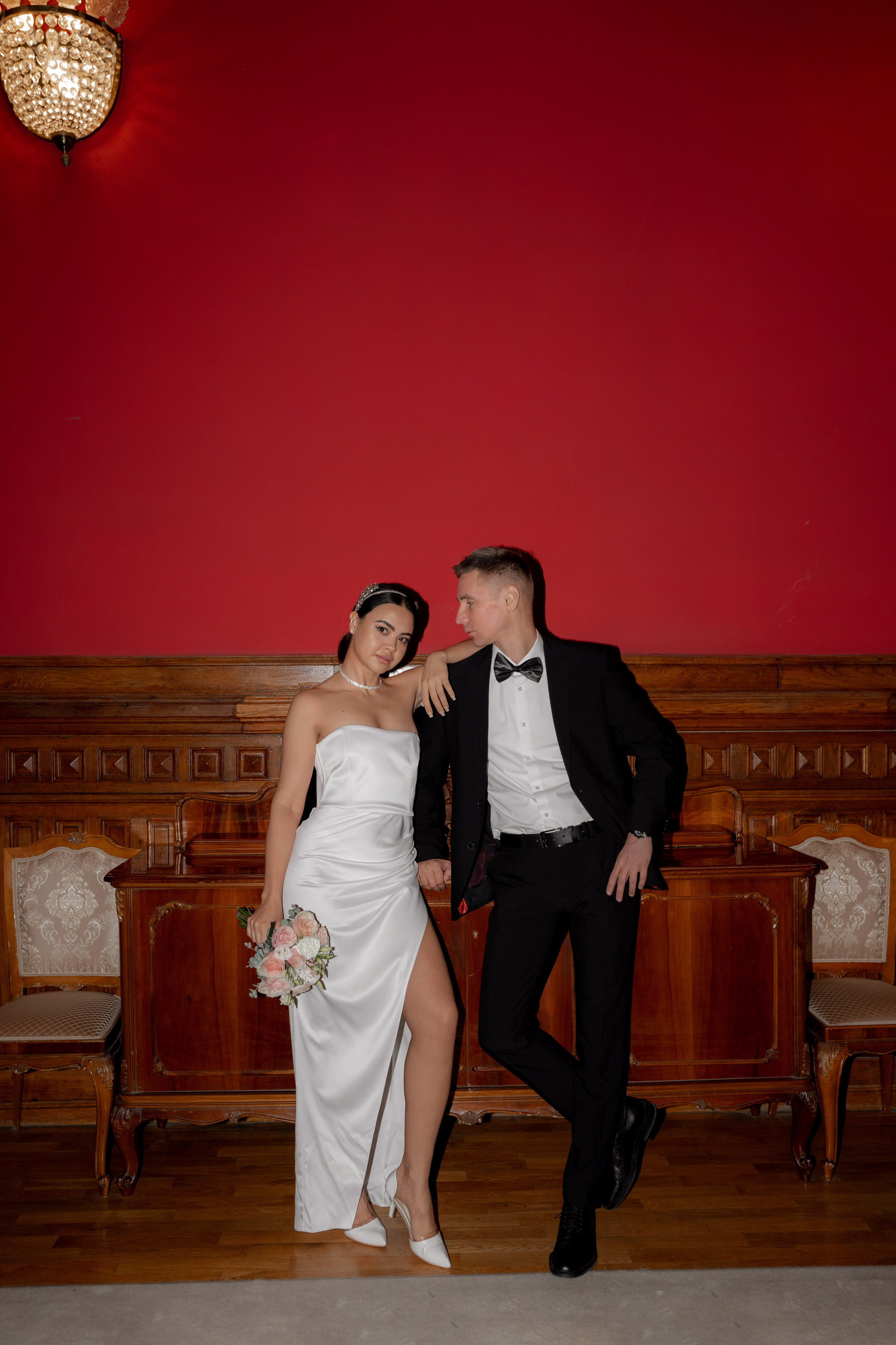 жених и невеста фотографируются на фоне красной стены во дворце бракосочетания 2 на фурштадской