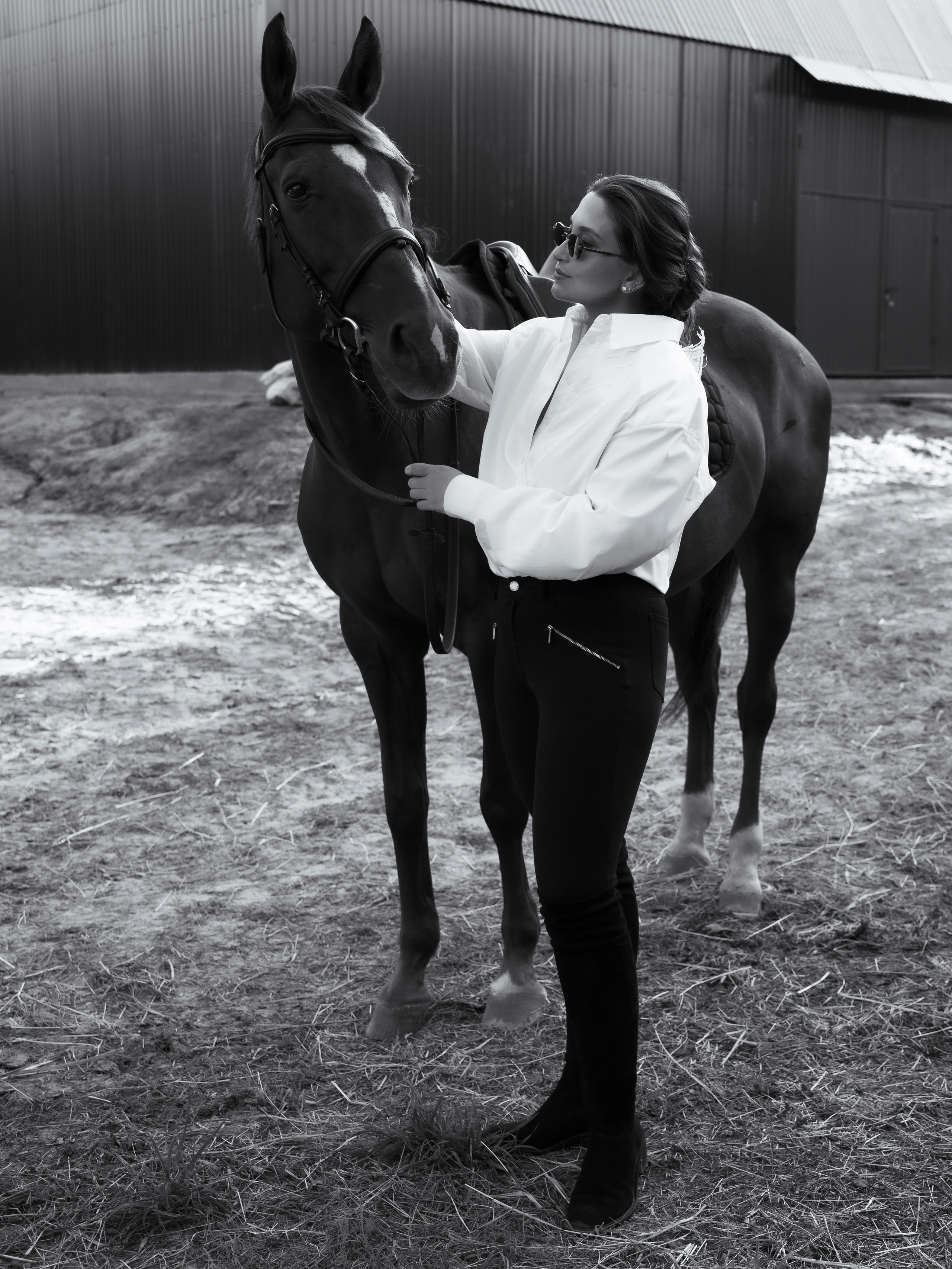 Красивая фотосессия девушки с лошадьми на конюшне в спортивном стиле наездницы