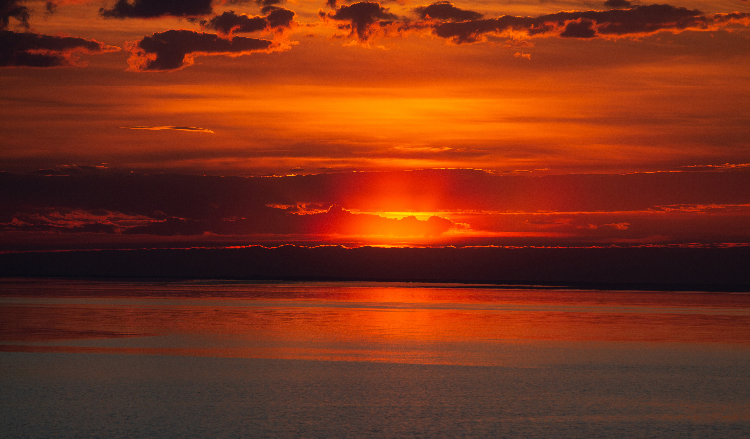 Солнце садится за горизонт над морем на закате. 