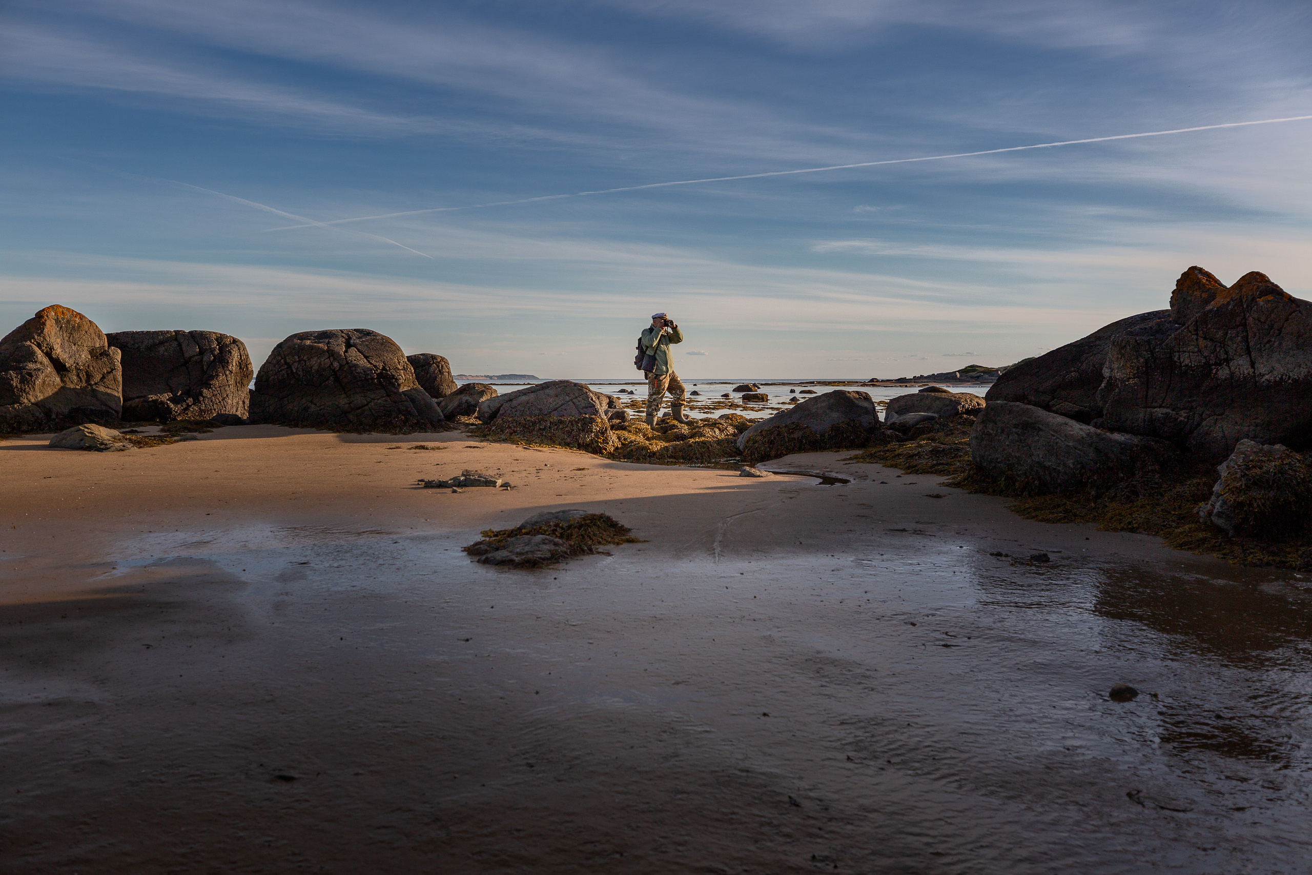Мужчина идёт по дну Белого моря во время отлива. 