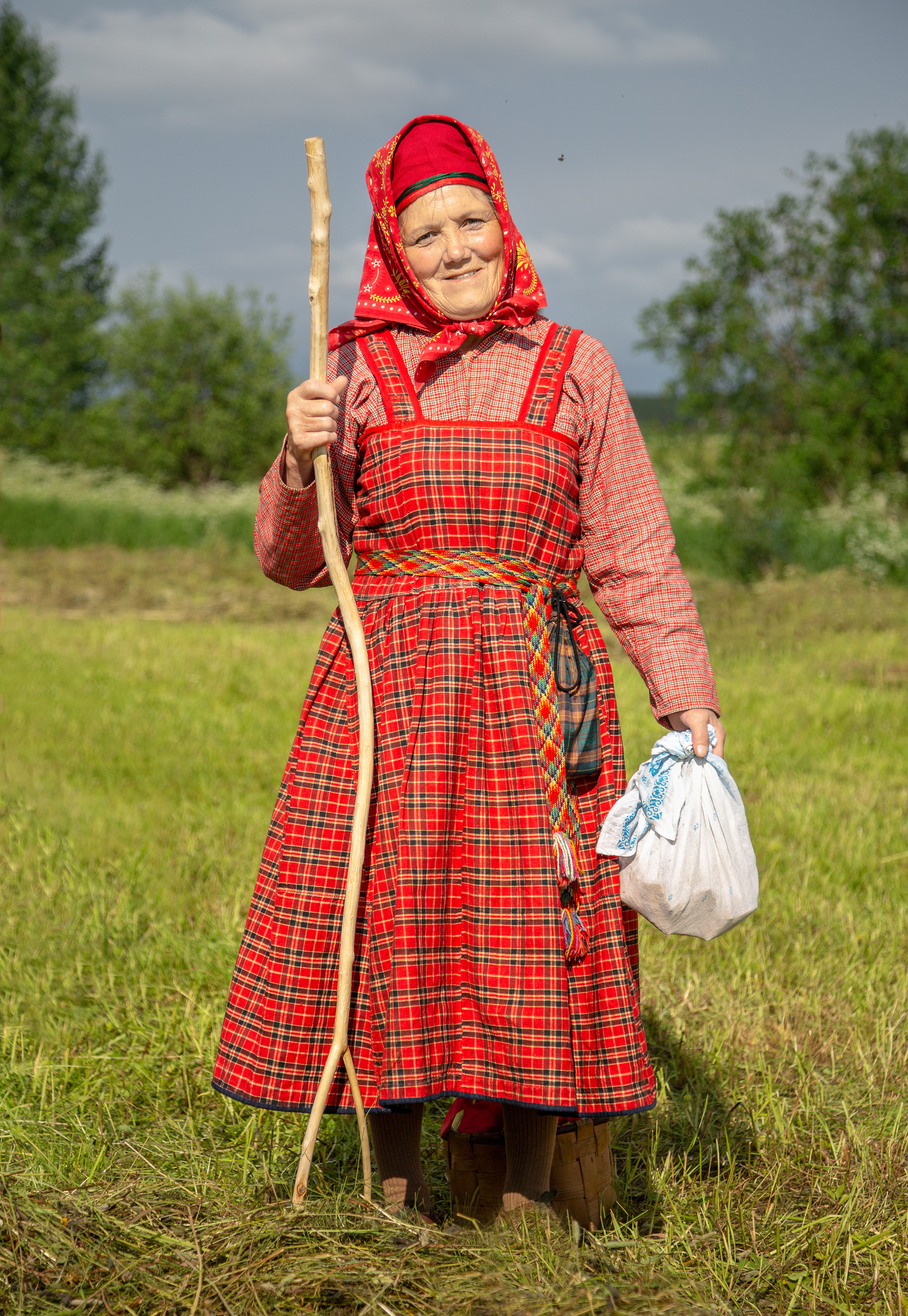 Старушка в красном сарафане с узелком и посохом. Деревня Веркола.