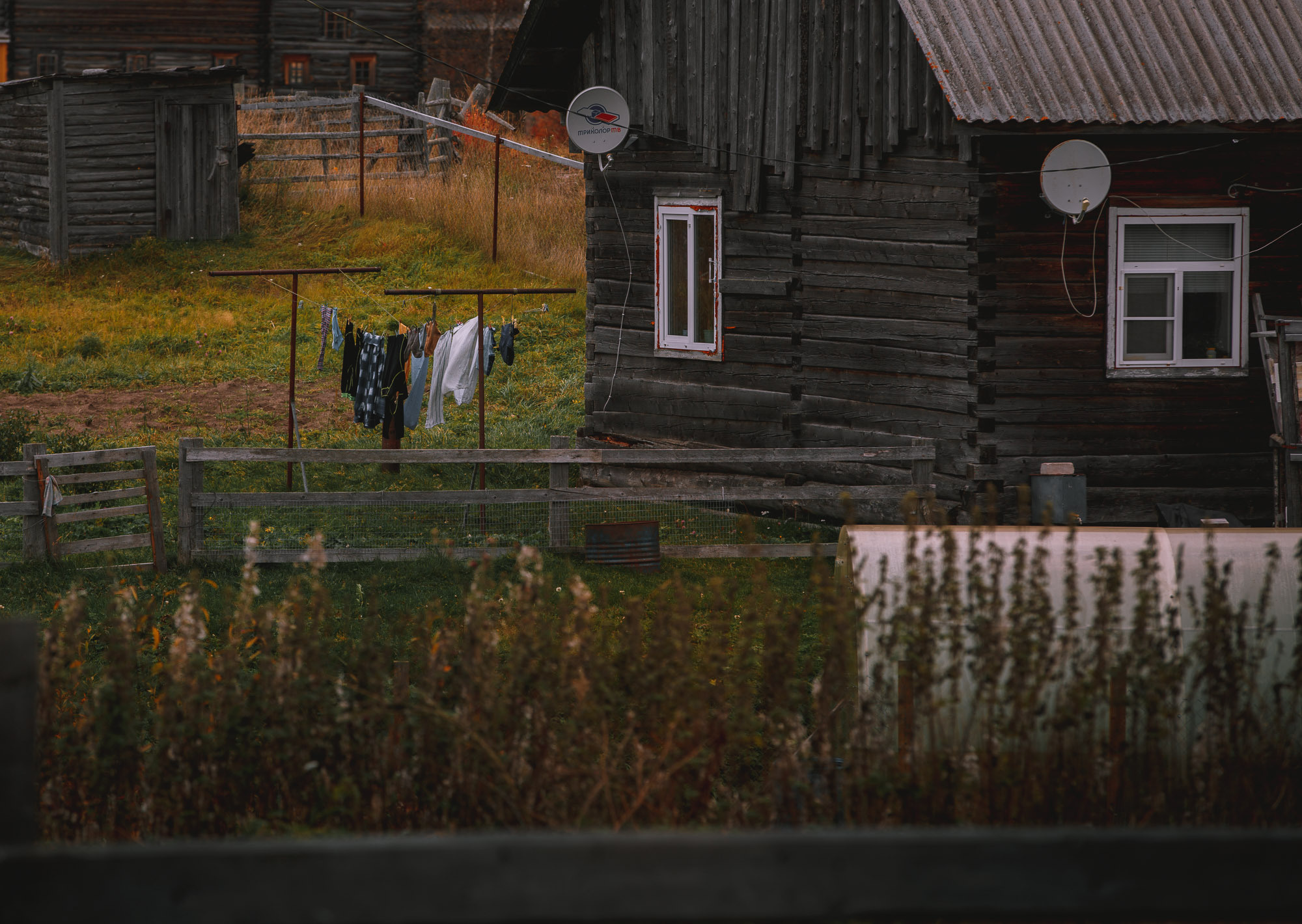 Белье на верёвке сушится во дворе деревенского дома. 