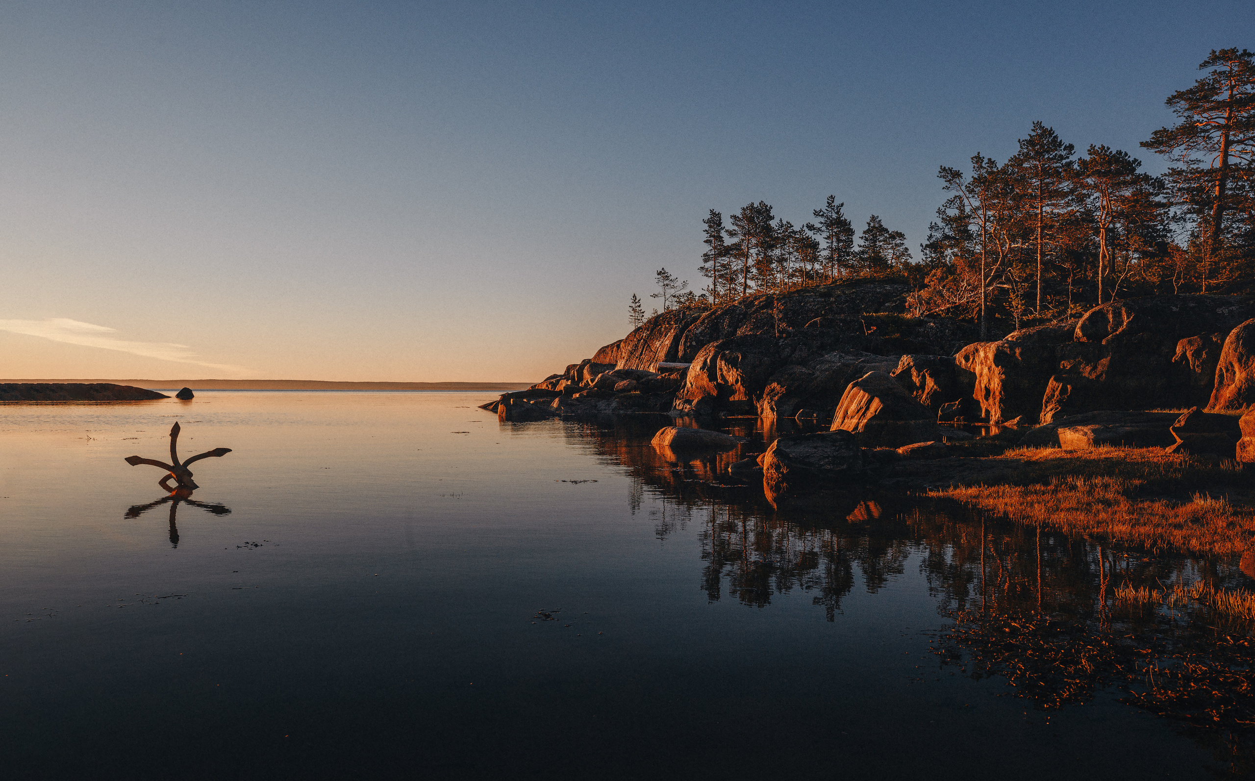 Старый якорь на берегу во время прилива в море. Рассвет. 
