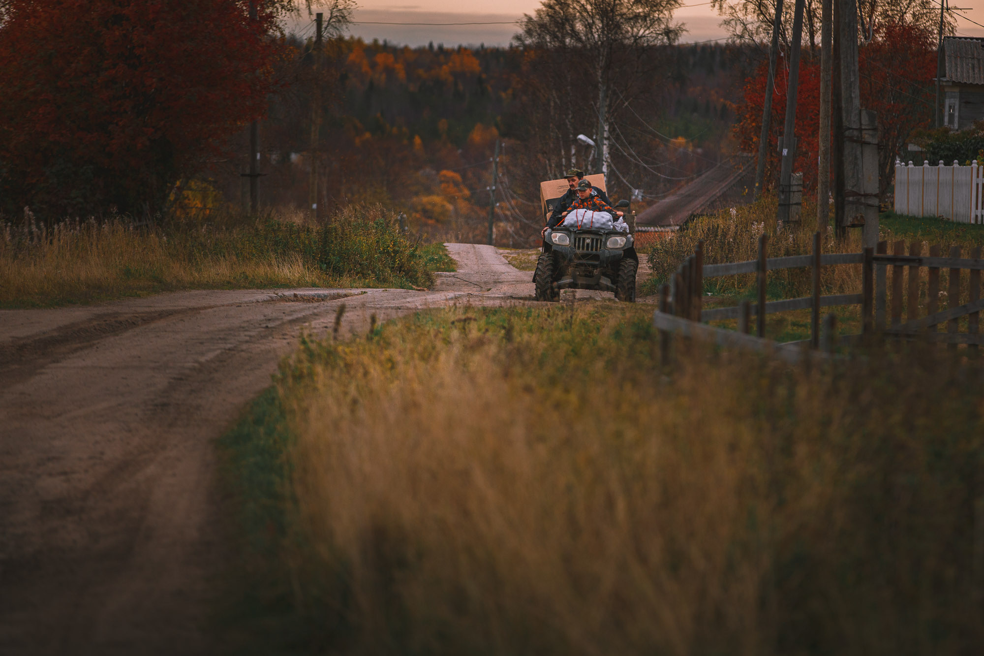 мужчина с ребёнком едет на вездеходе, каракате по деревенской дороге. 