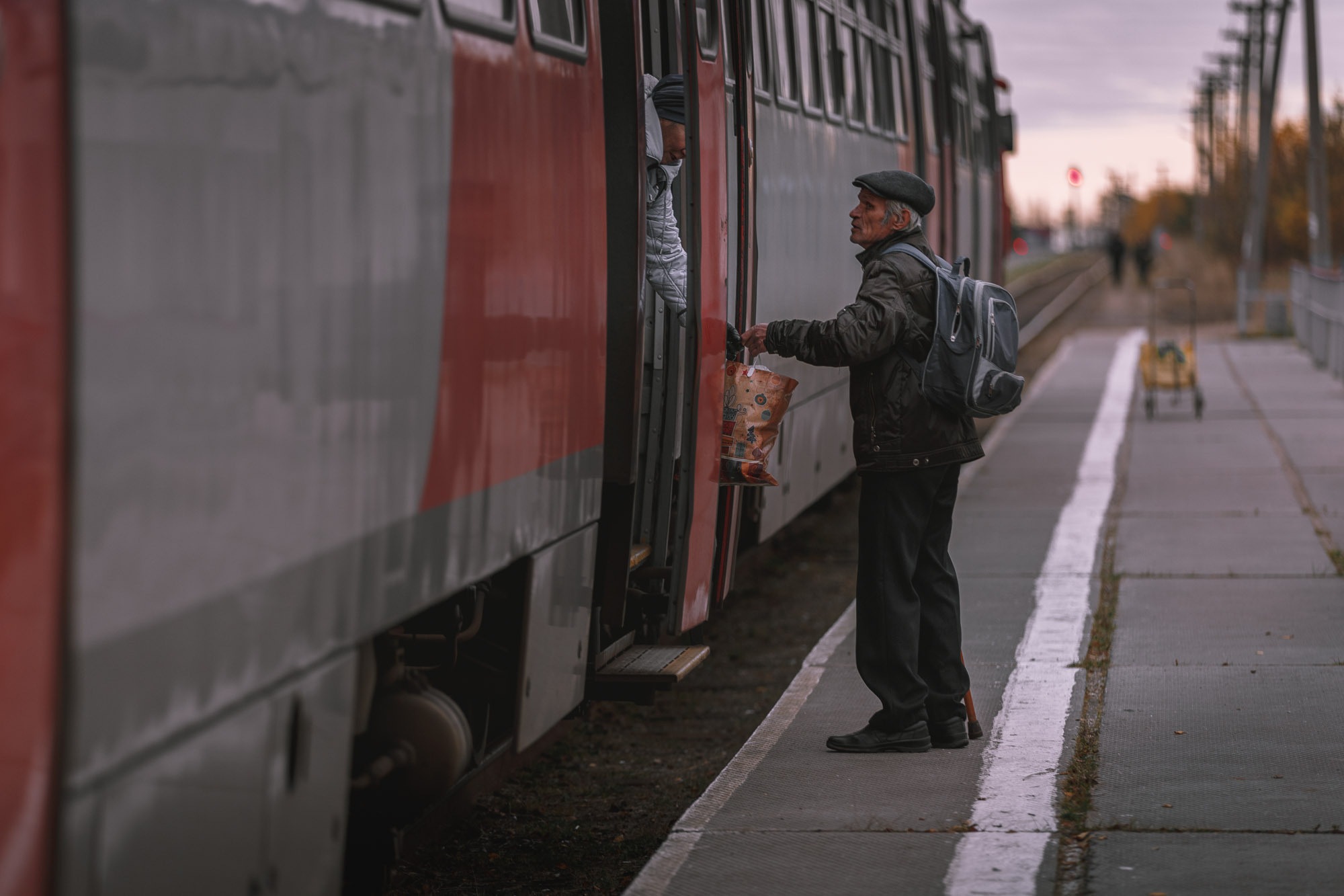 На пероне старик провожает жену и сажает её в вагон. 