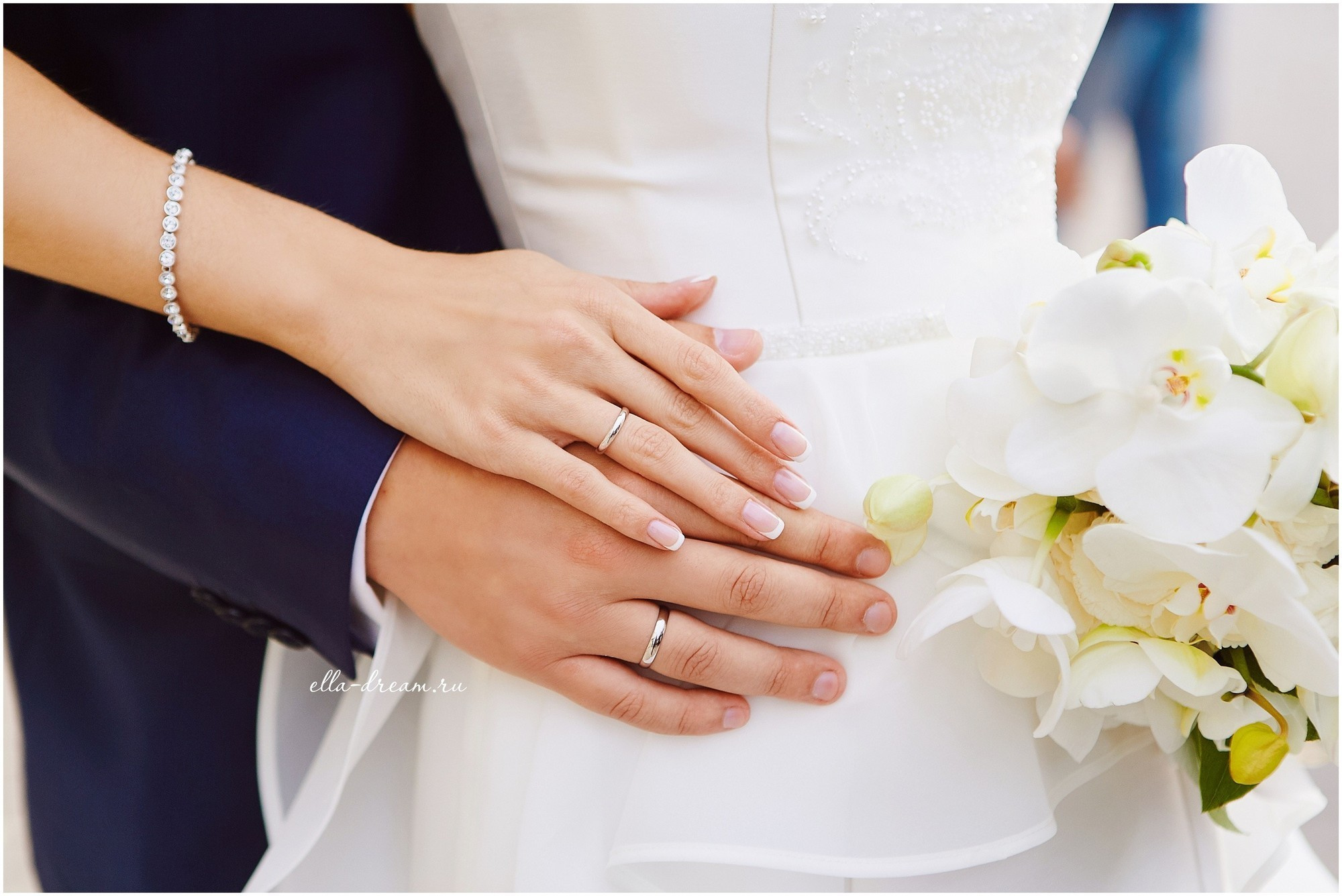 руки жениха и невесты с букетом из орхидей