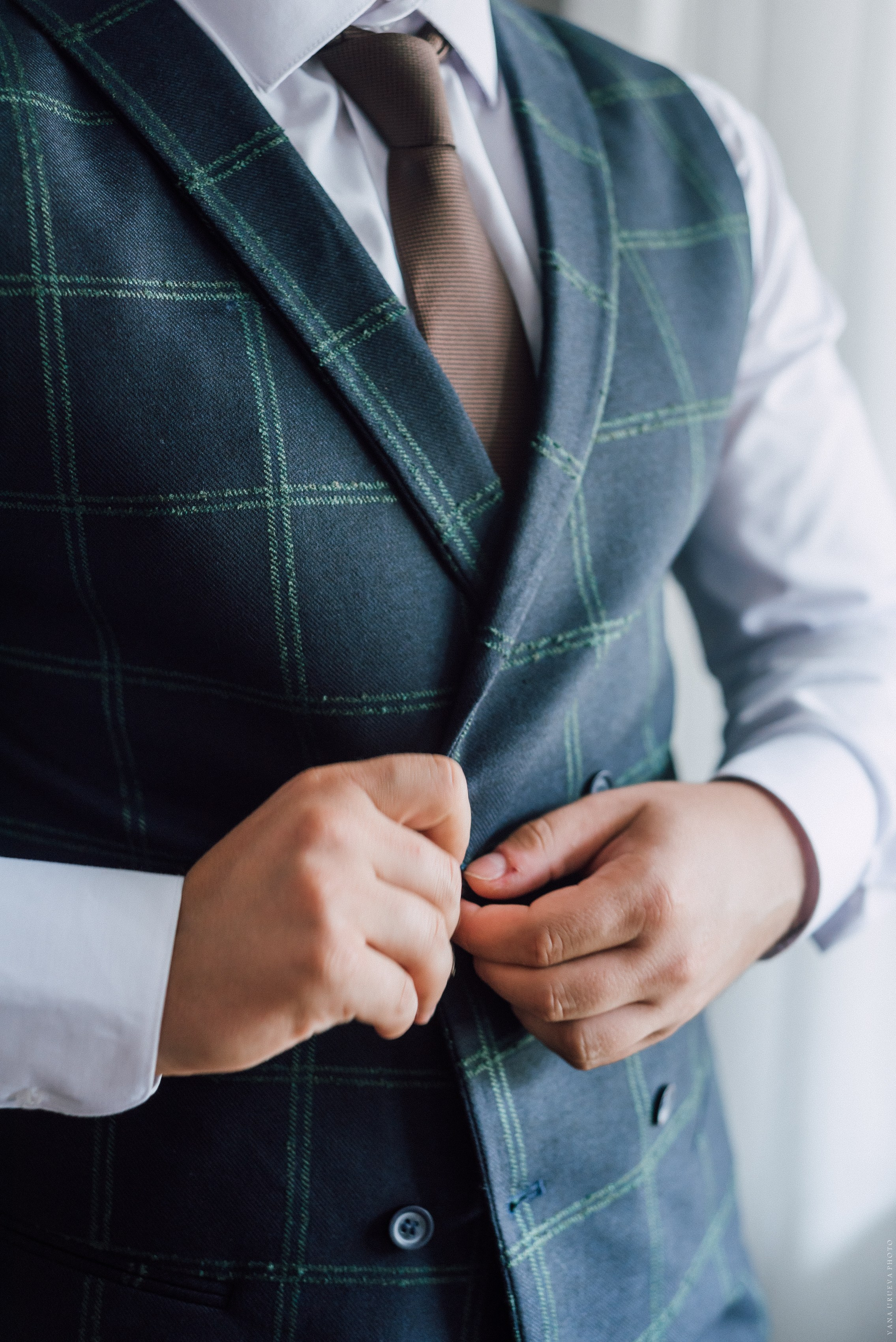 Жених застегивает жилетку 