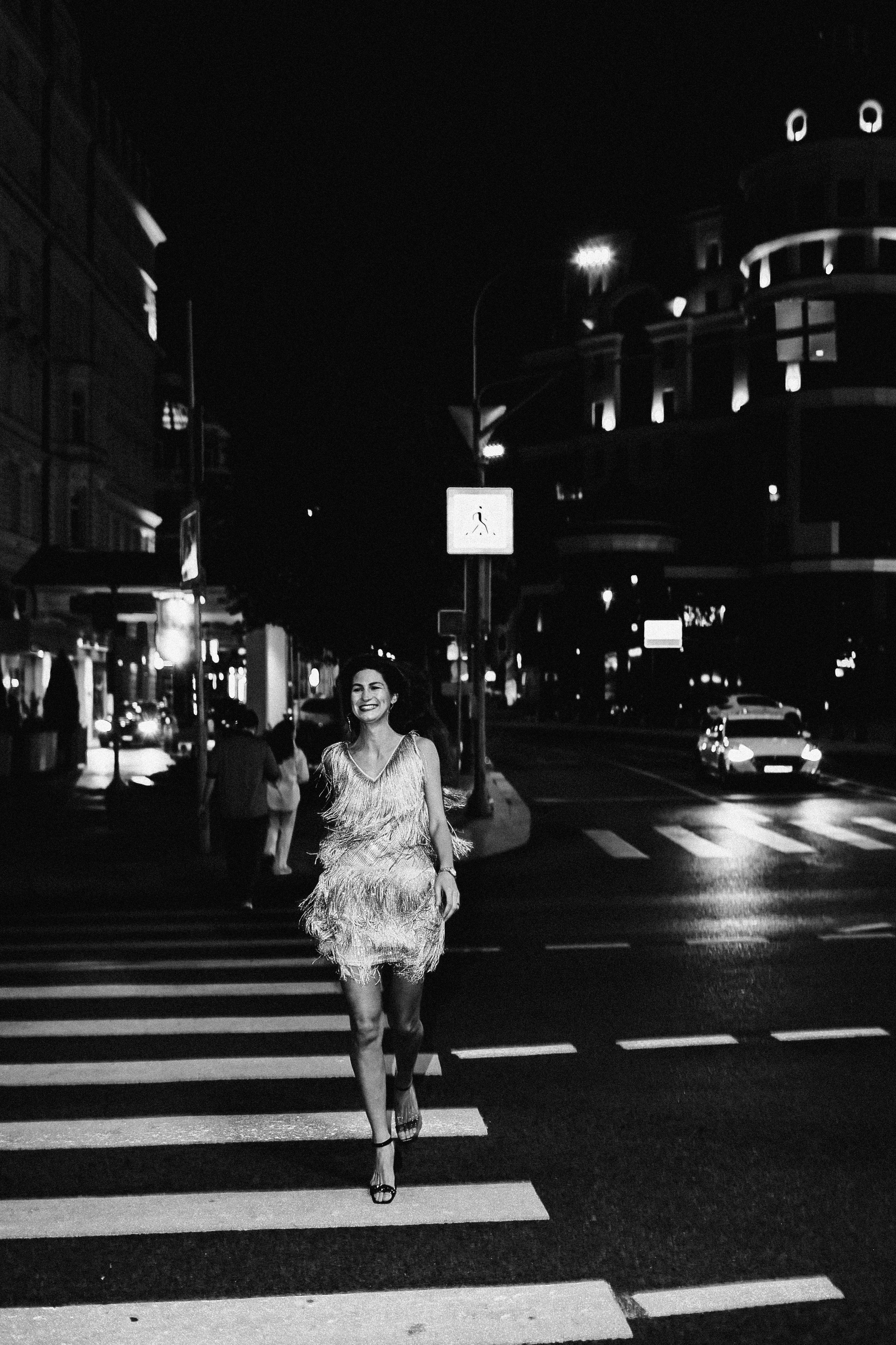 <img src="IZ0A0352.jpg" alt="Красивая девушка в блестящем платье с бахромой бежит по  ночному городу по пешеходному переходу">