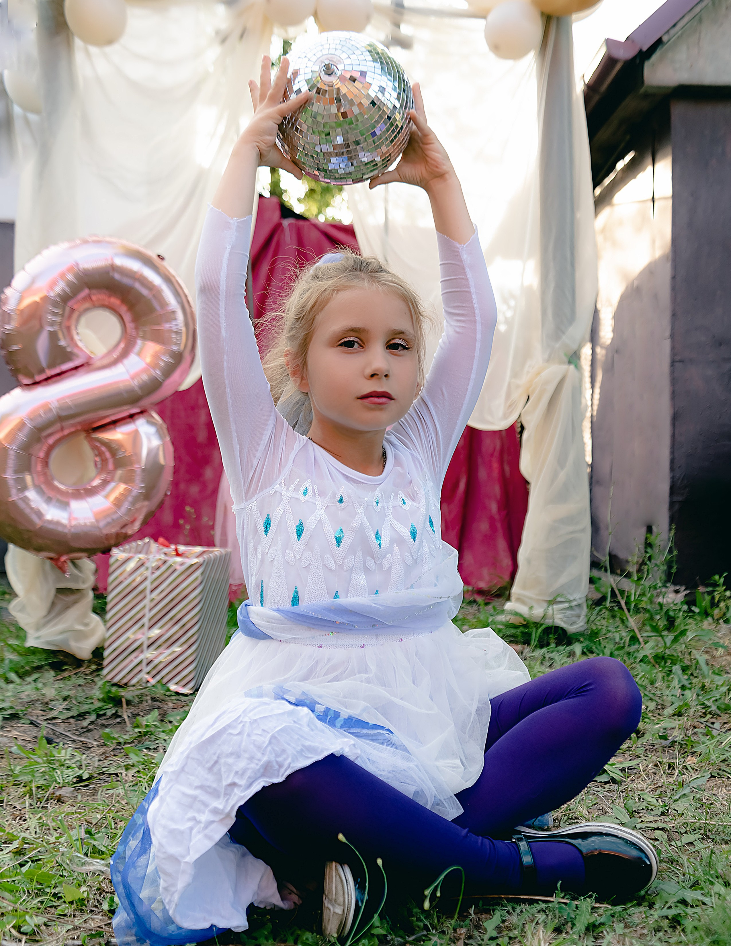 На фото девочка сидит с шариком.