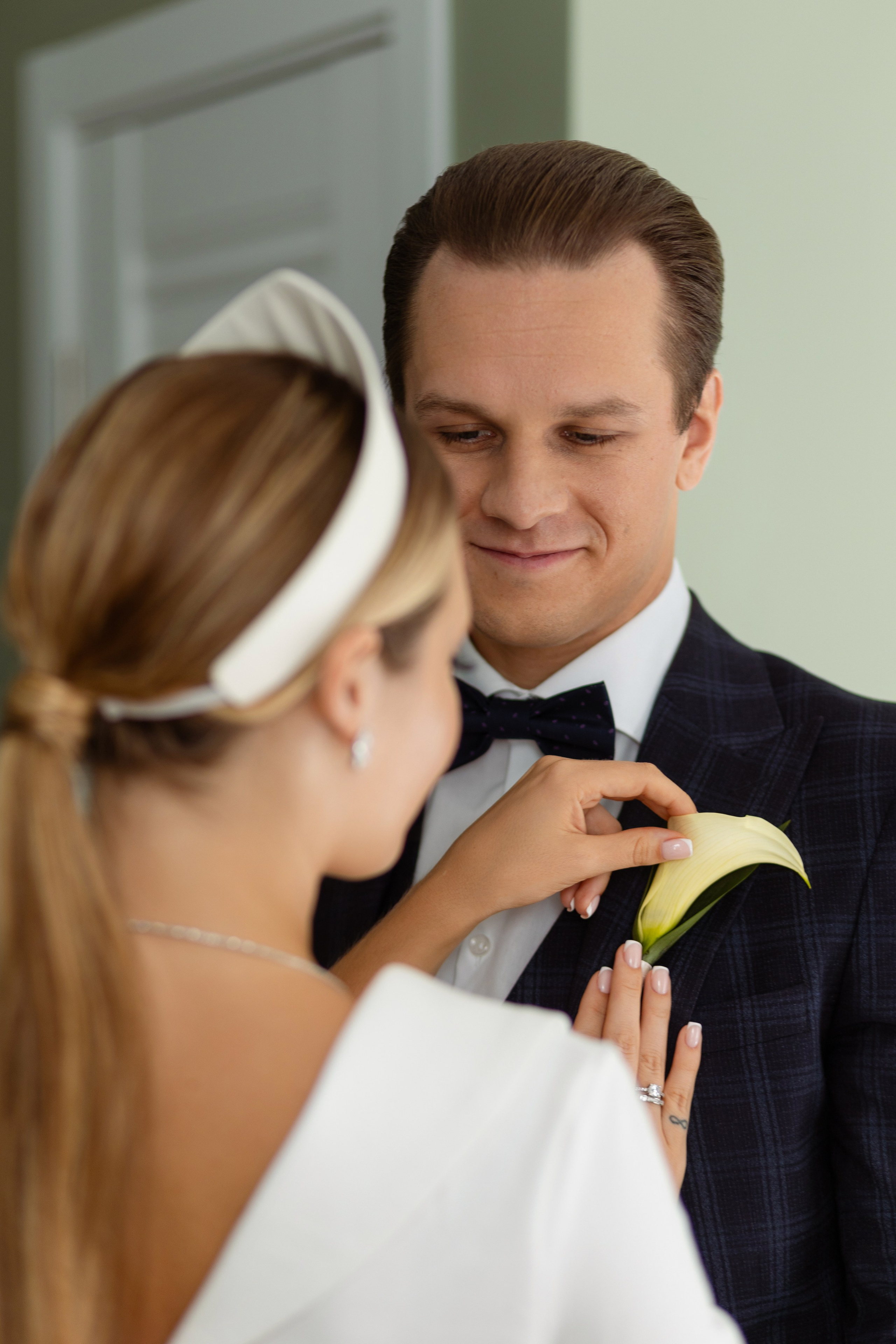 Невеста поправляет бутоньерку на пиджаке жениха.