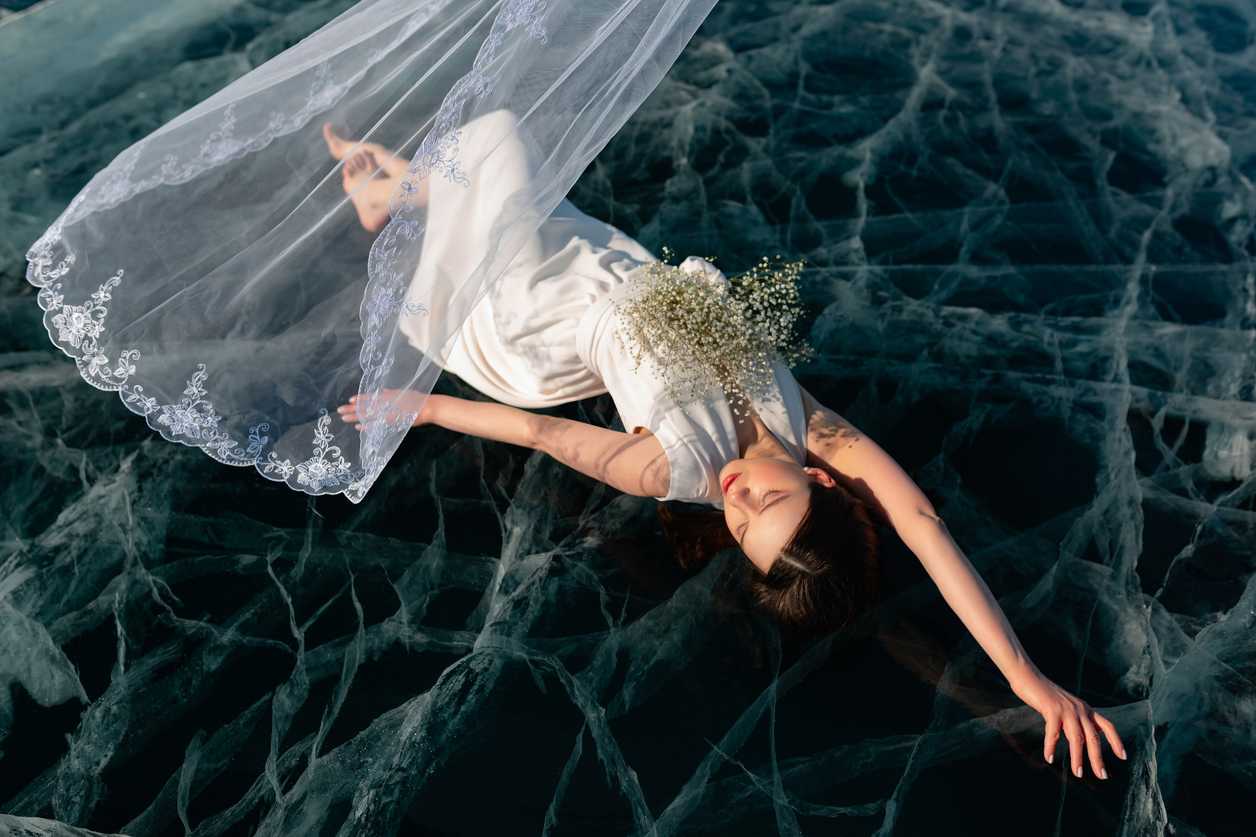 Невеста в белом платье лежит на льду Байкала