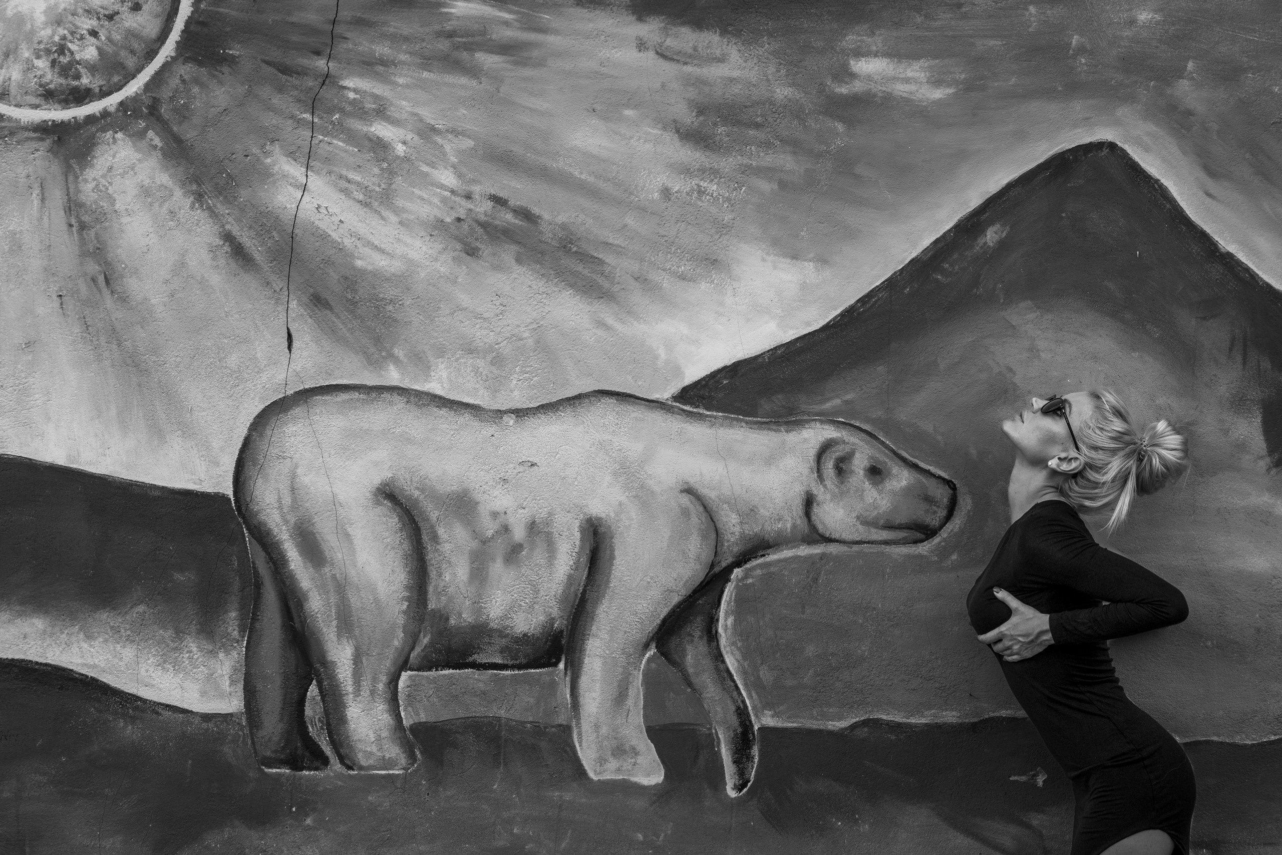 Девушка в платье на фоне граффити с медведем.