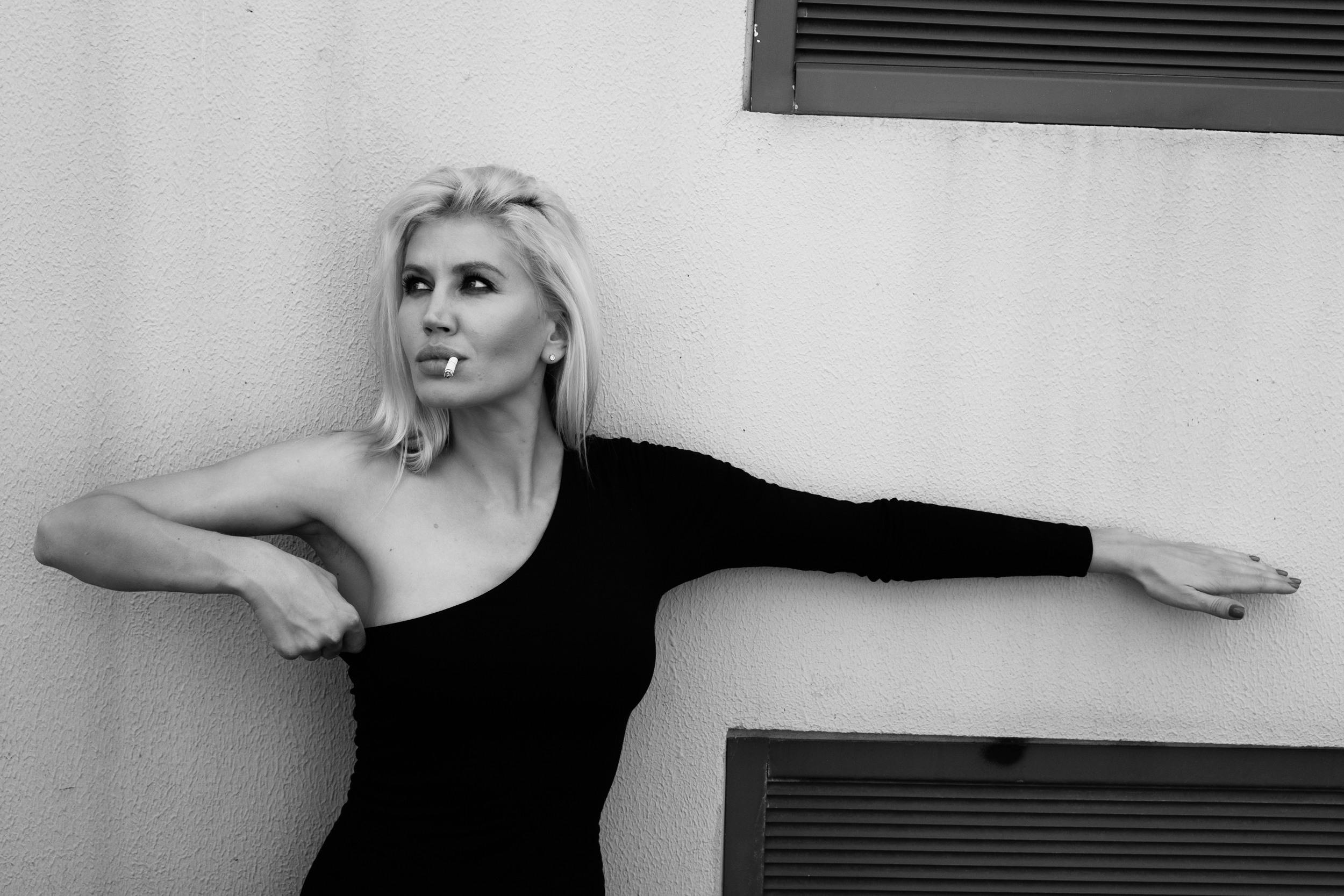 Девушка поправляет платье и смотрит в сторону.