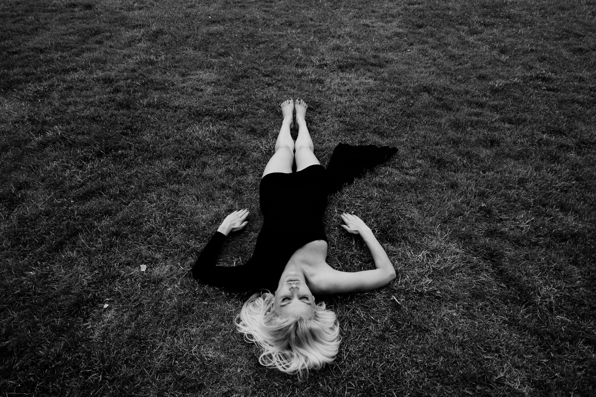 Девушка в платье лежит на траве.