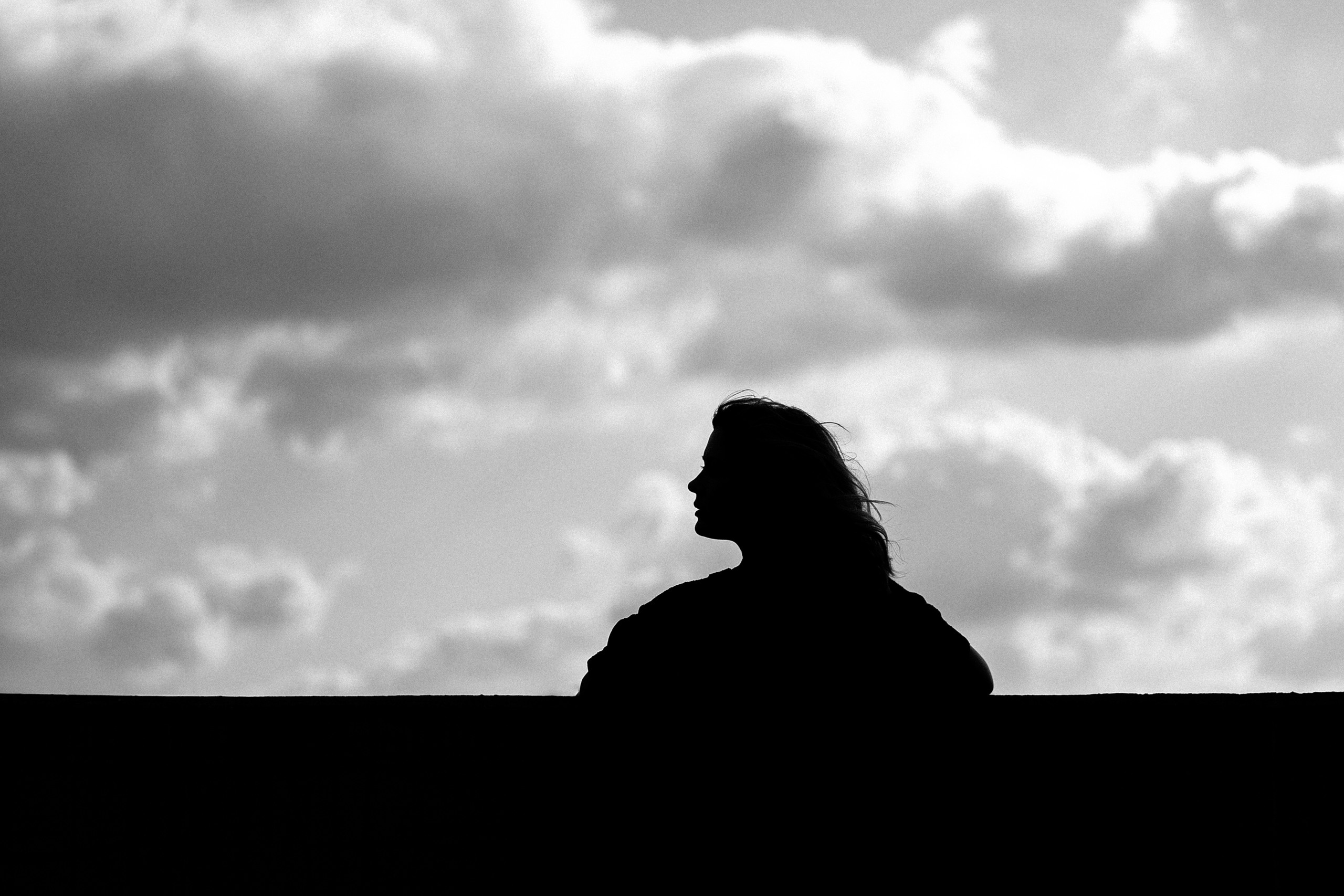 Силуэт девушки на фоне облаков.