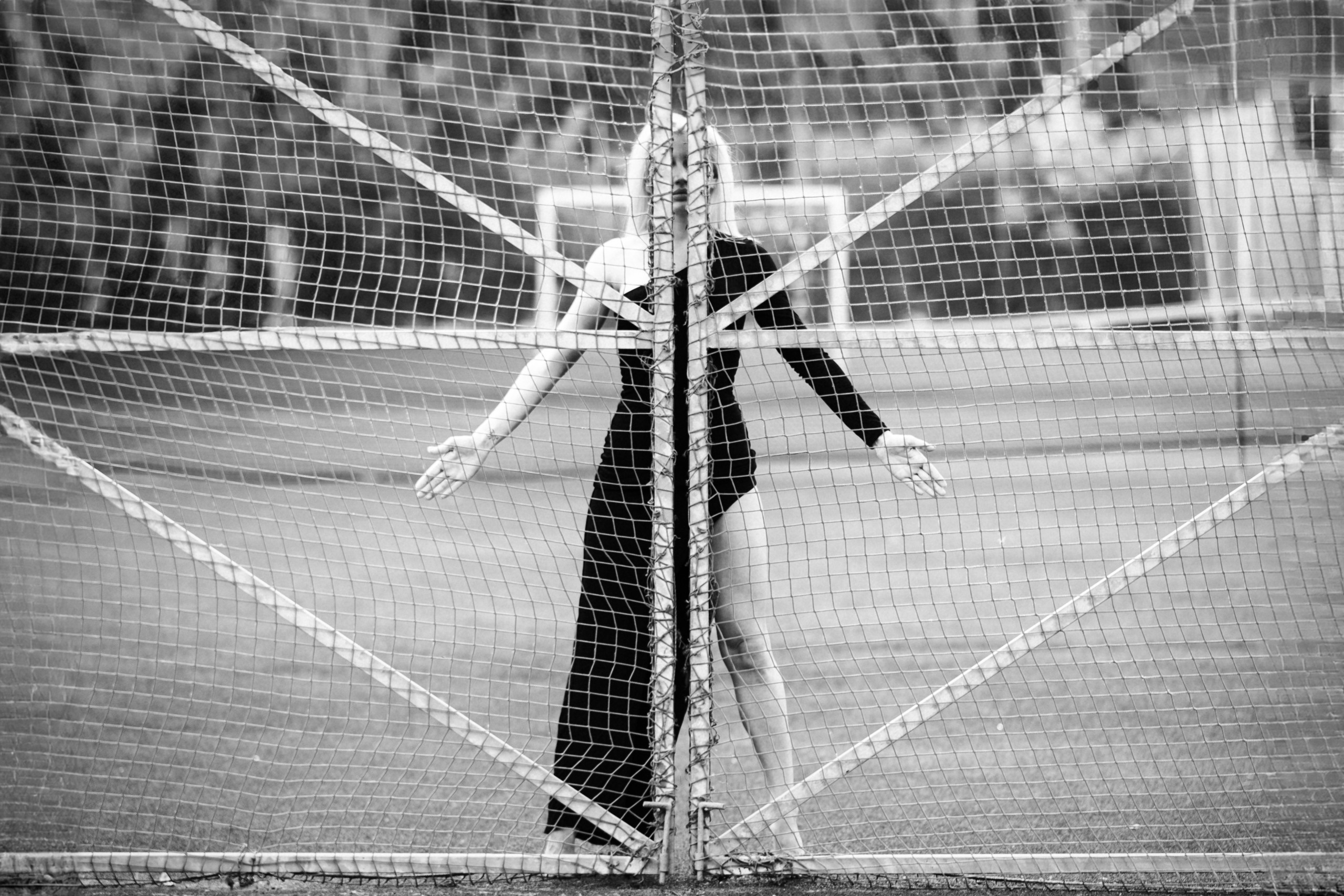 Девушка стоит за сеткой.