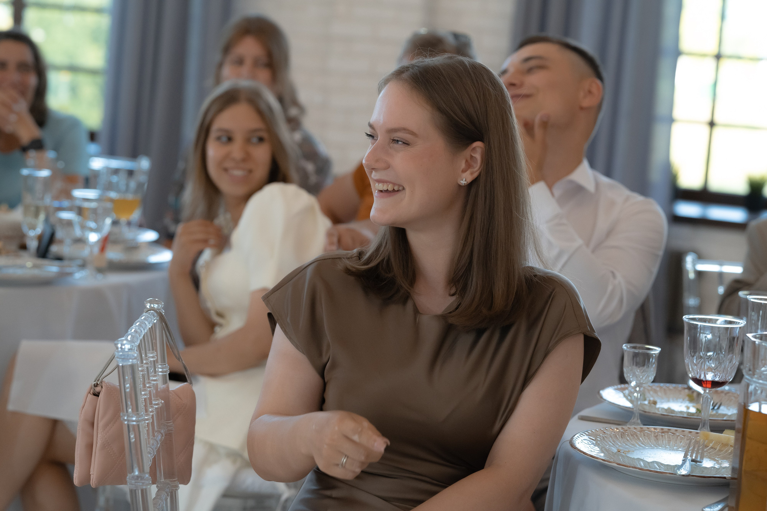 Реакция гостей за столами на речь — улыбки и аплодисменты во время свадебного ужина