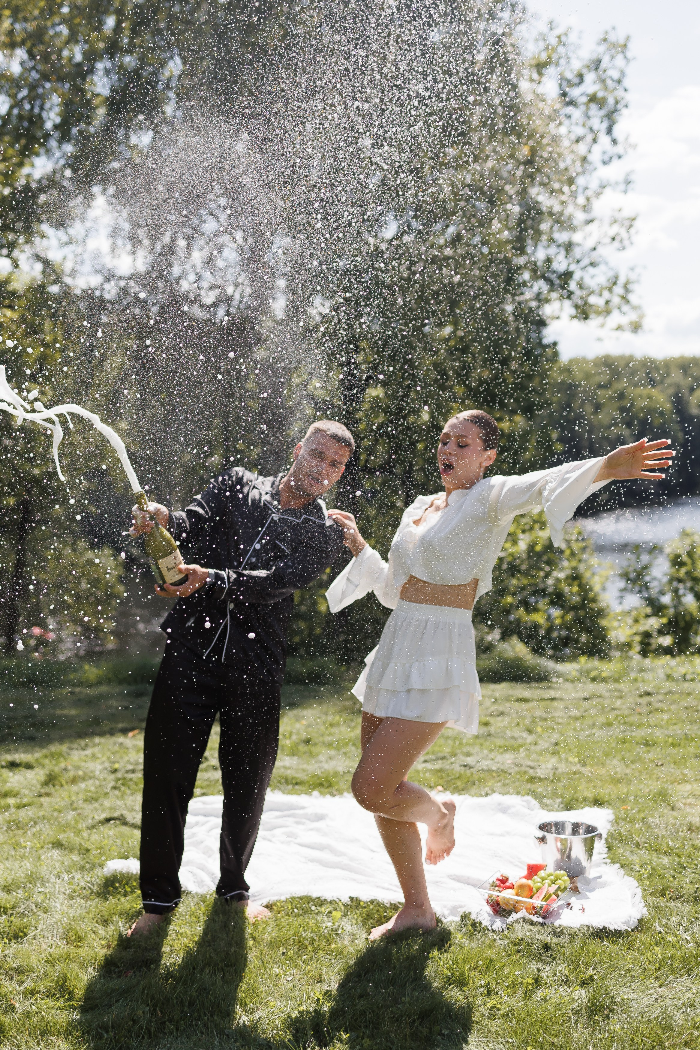 Жених с невестой открывают бутылку шампанского и все в брызгах