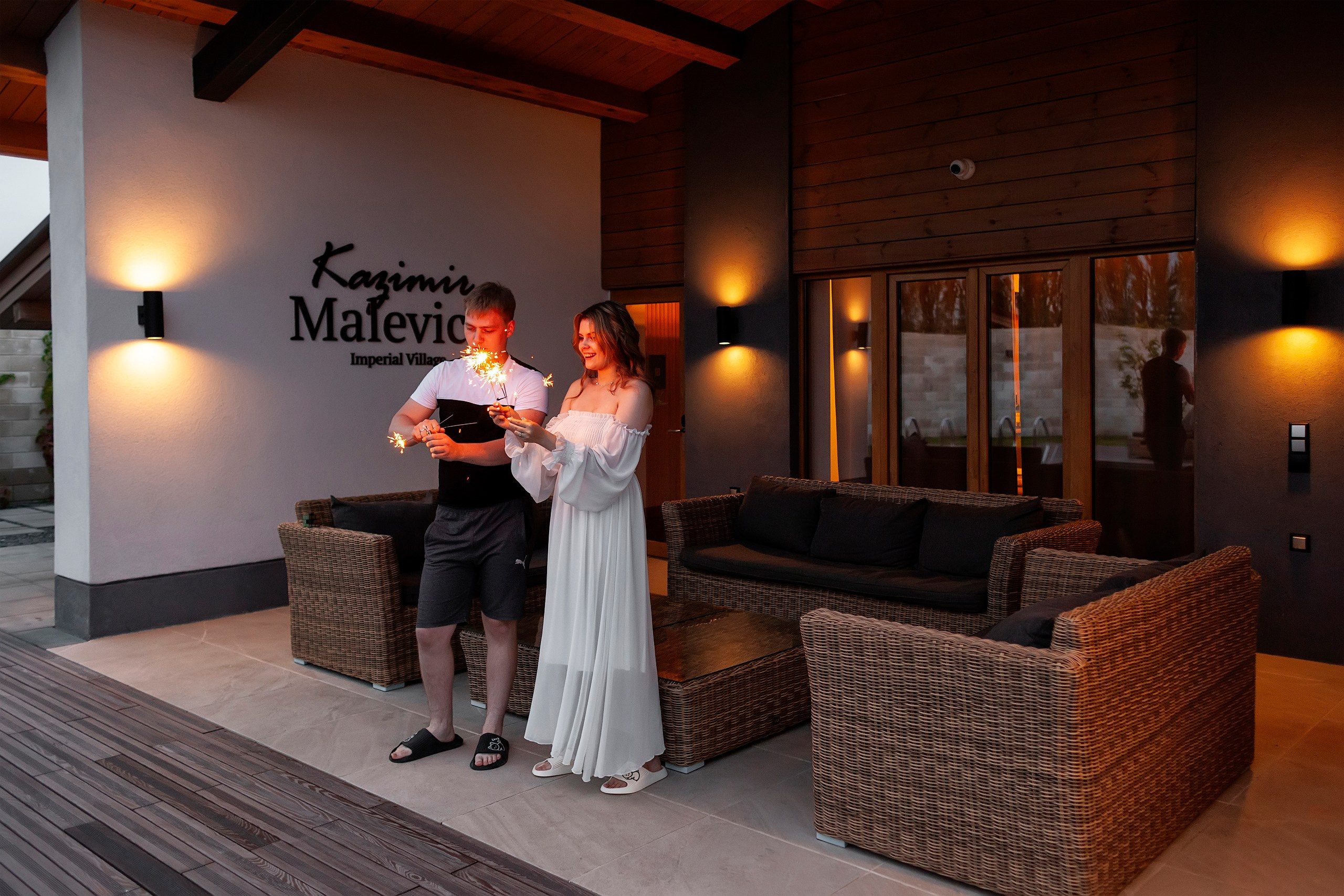 Пара около бассейна радуется искрам бенгальских огней 