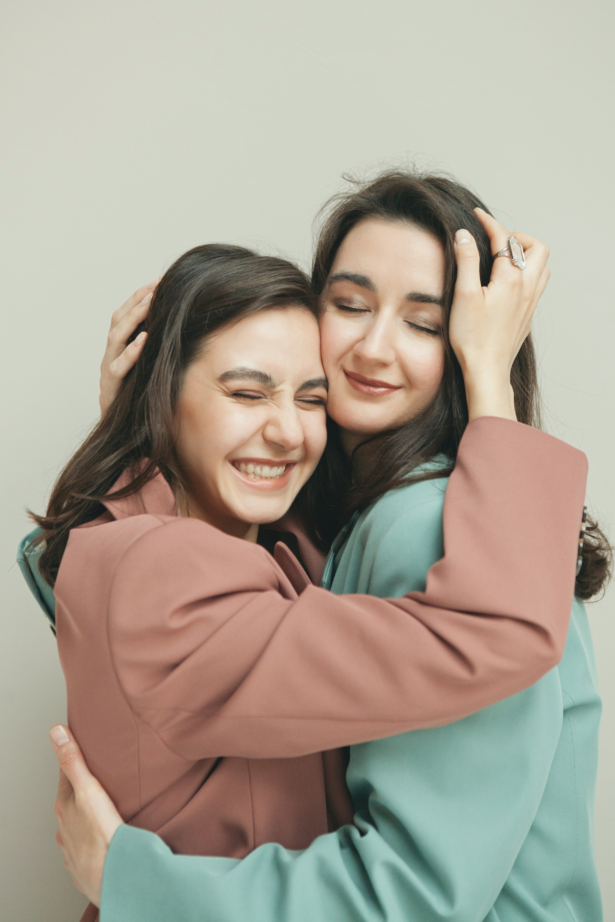 две сестренки обнимаются и улыбаются с закрытыми глазами