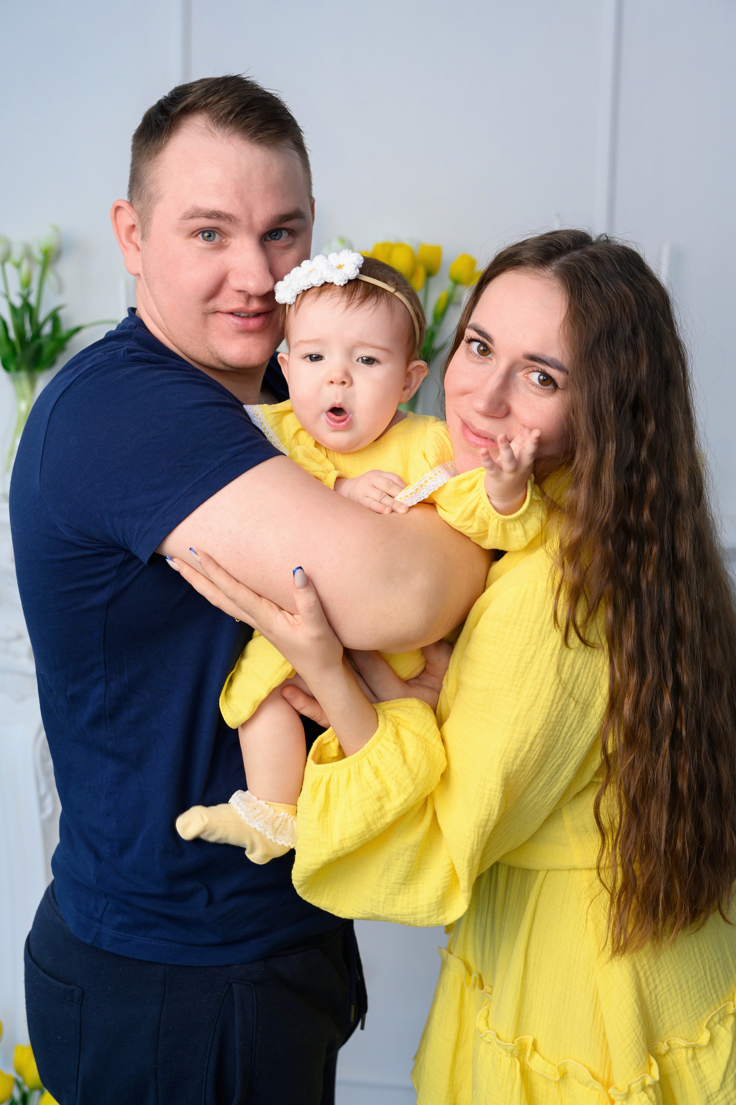 Мама и папа держат на руках свою маленькую дочку