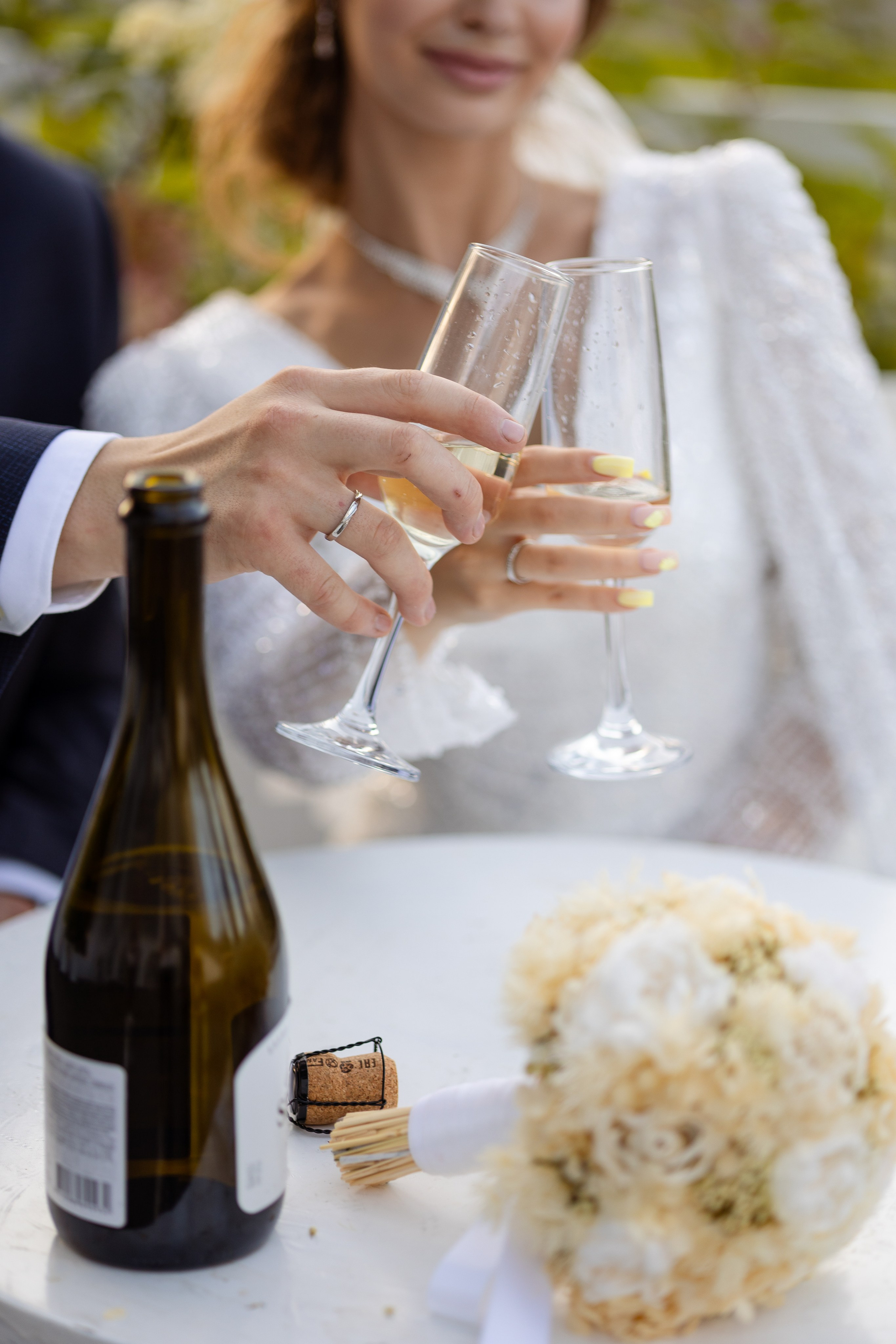 На переднем плане руки  молодых с бокалами шампанского.