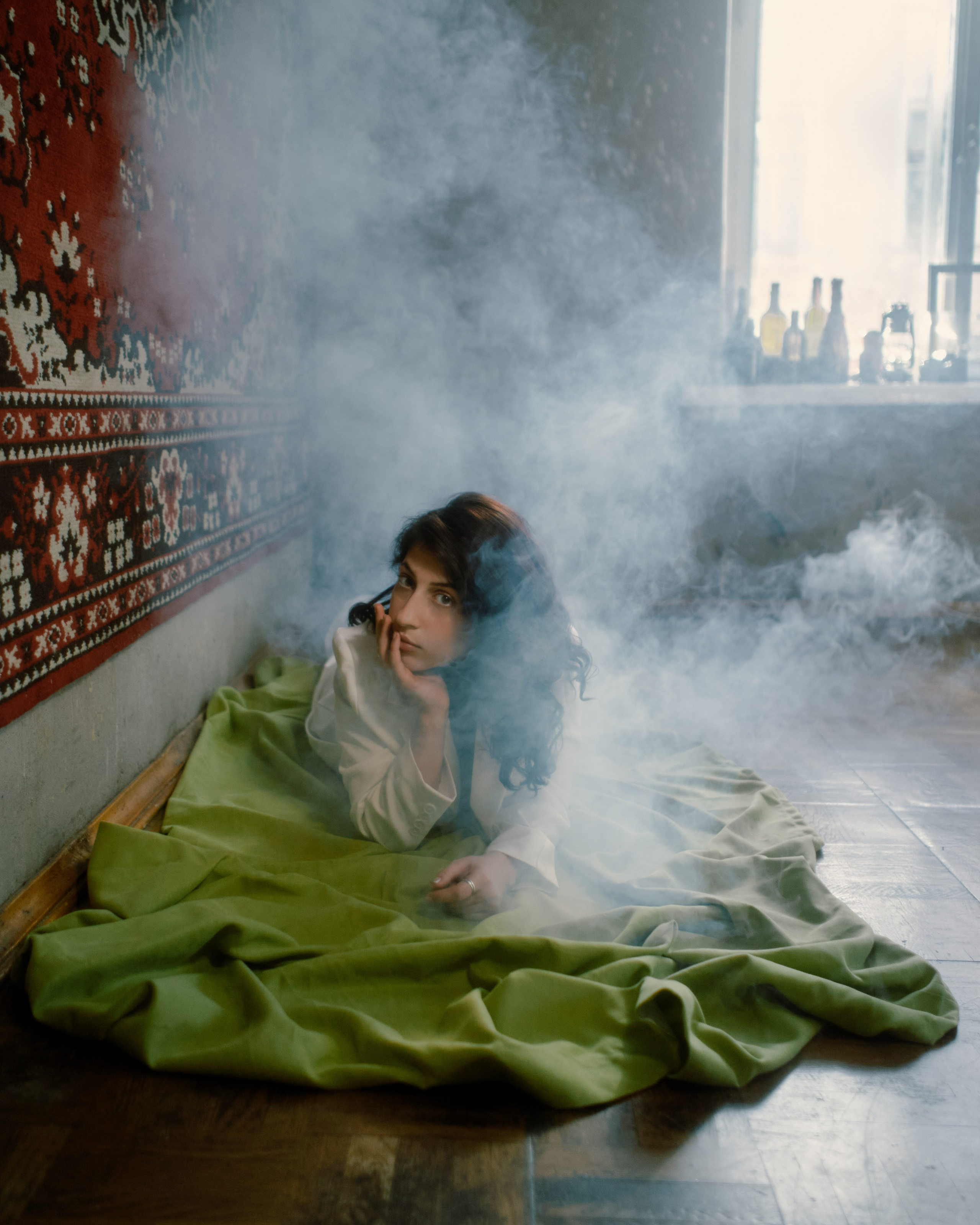 Женская фотосессия в дымке, девушка лежит на зеленой ткани, авторский портрет в кинематографичном стиле от фотографа в Петербурге