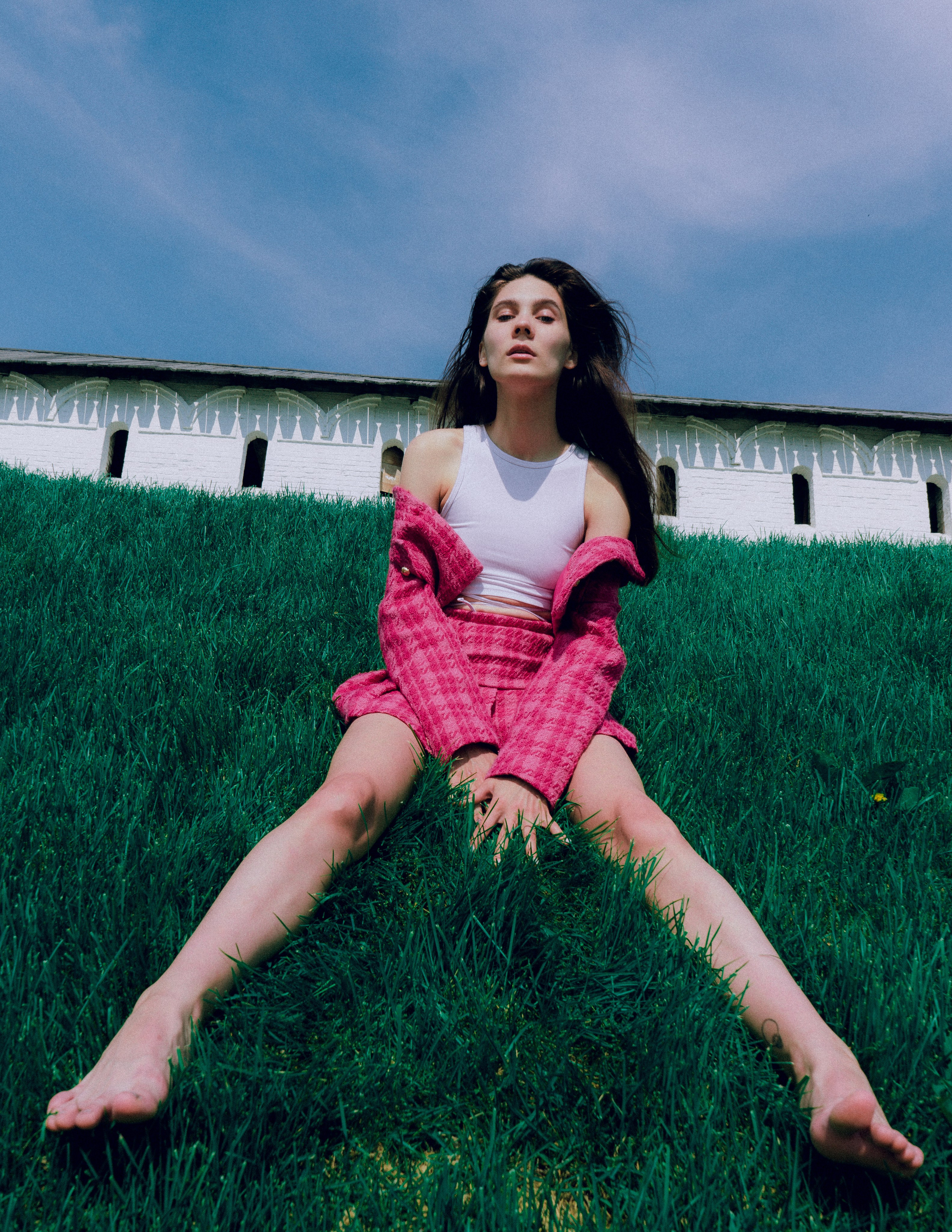 На переднем фоне сидит девушка в розовом костюме, на задней фоне — Казанский Кремль 