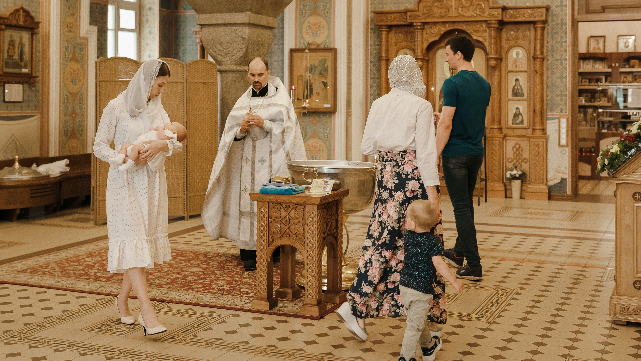 Священник и крестные родители делают обход купели в  красивом храме в Воронеже