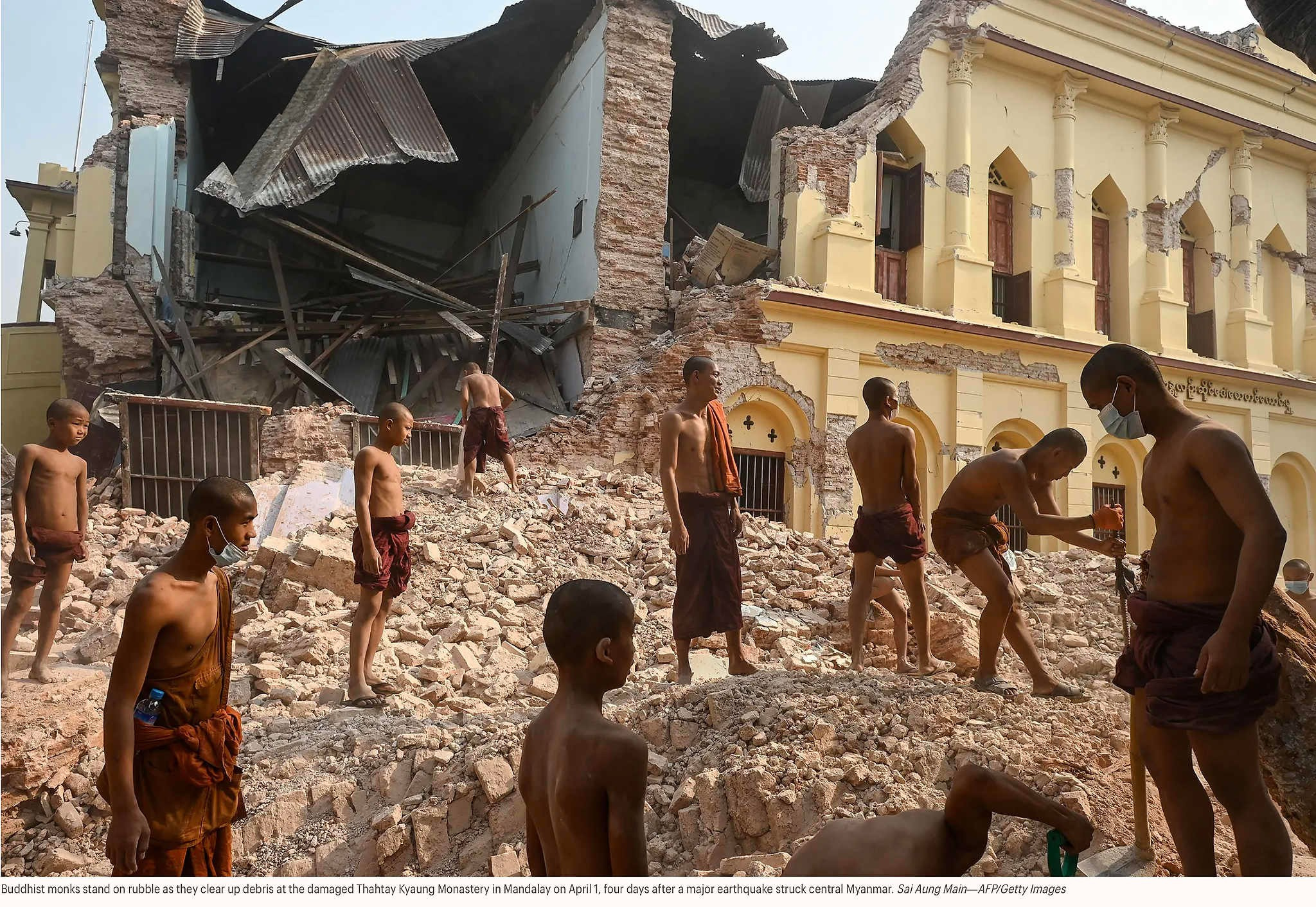 Буддийские монахи стоят на обломках, расчищая завалы в разрушенном монастыре Татай Кьяунг в Мандалае 1 апреля, через четыре дня после сильного землетрясения в центральной части Мьянмы. Сай Аунг Мэйн — AFP/Getty Images