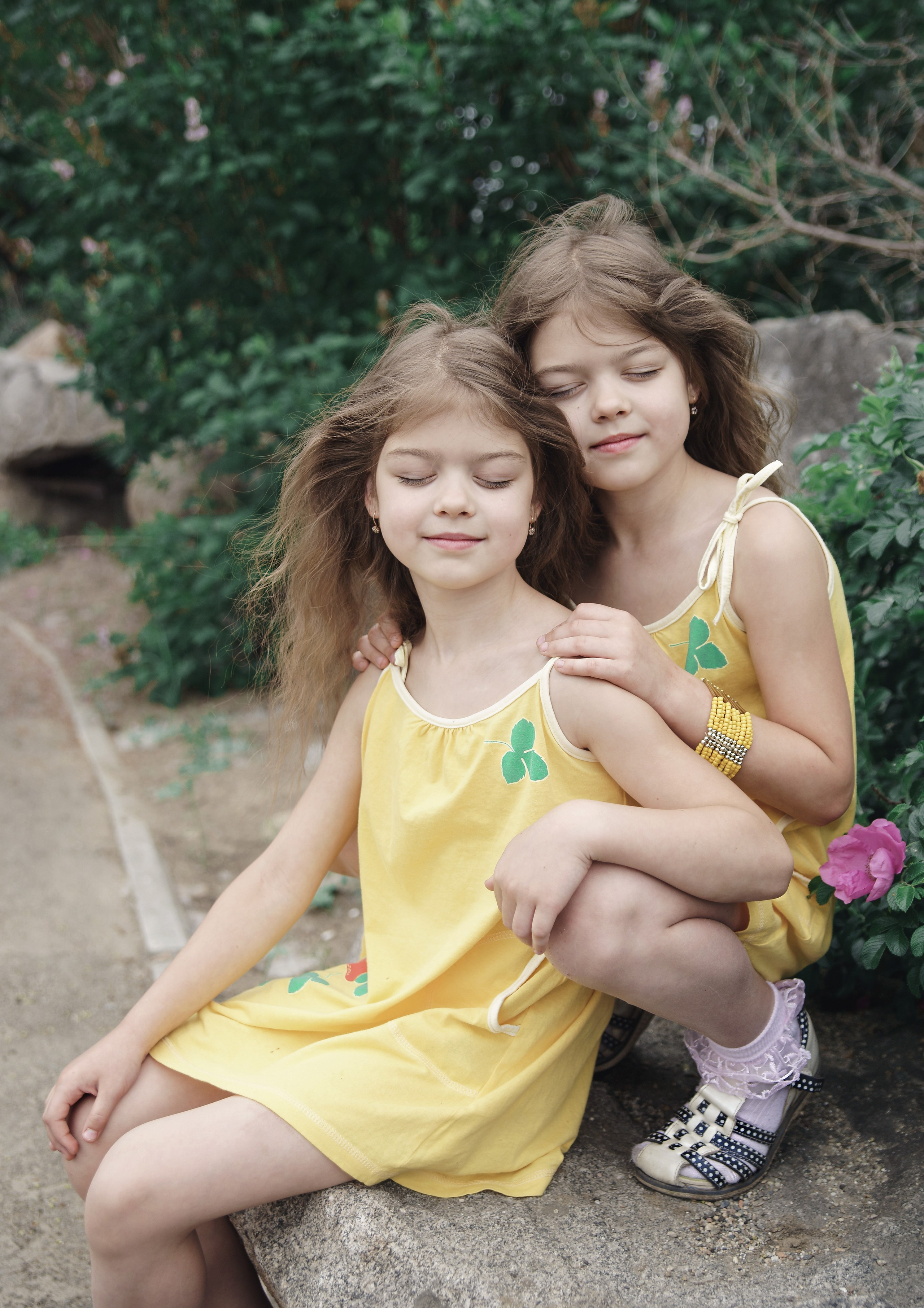 Детская фотосессия летом - сестры обнимаются с закрытыми глазами