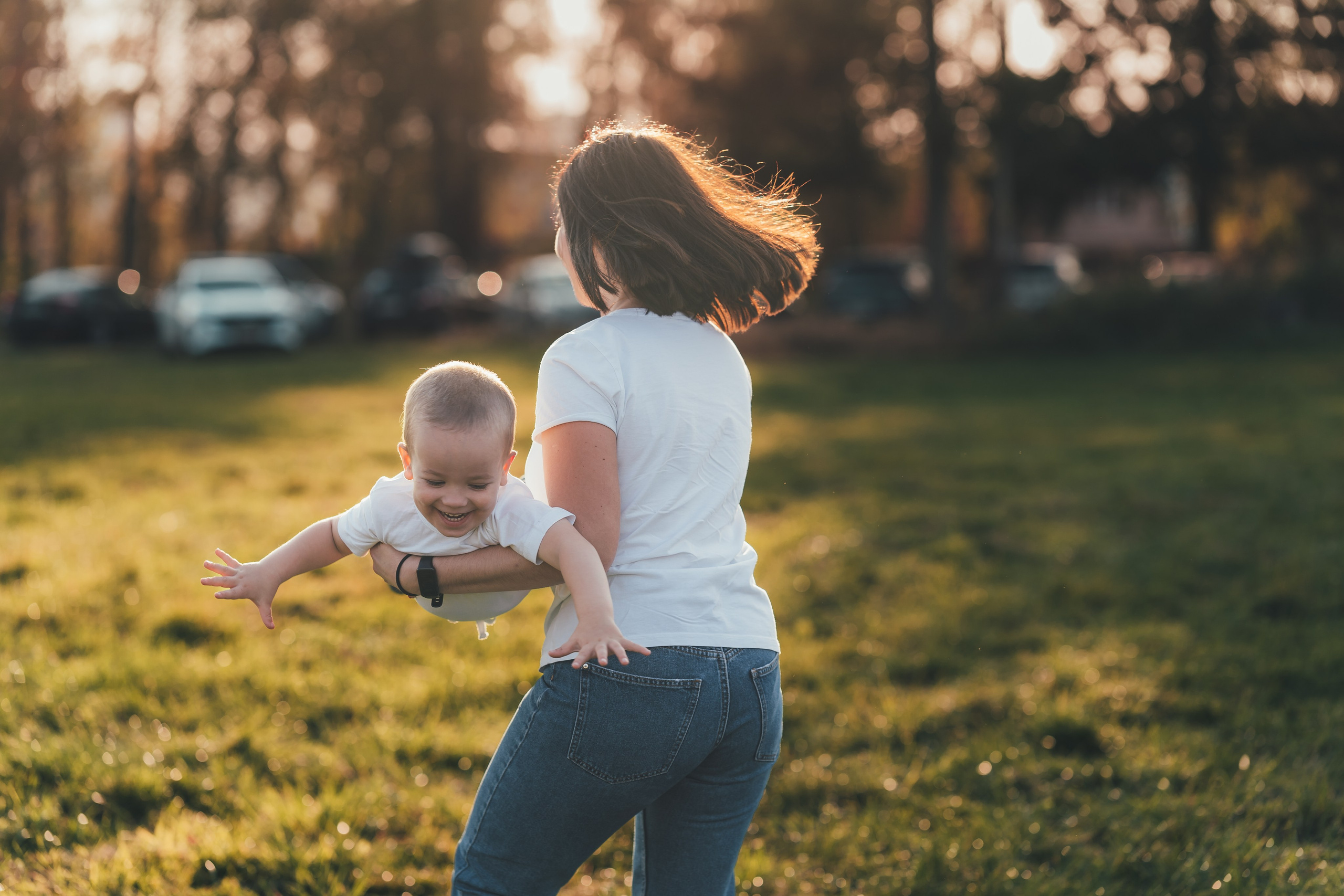 Мама играет с сыном катая его на руках как самолетик