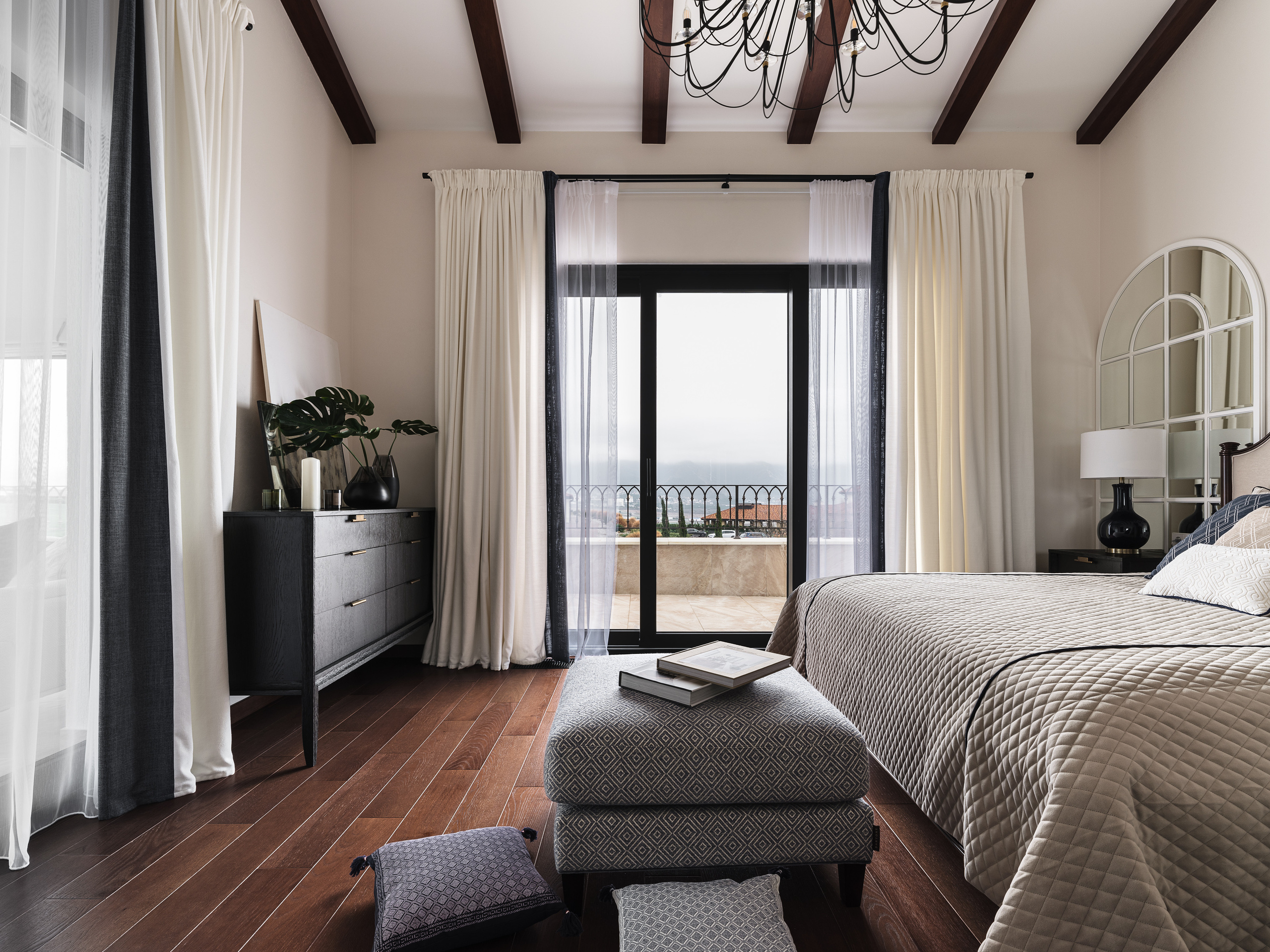 Современный интерьер спальни с кроватью, пуфом, чёрным комодом и панорамными дверями с выходом на террасу; дизайн и оформление Валерии Хростовской, стилистика и фотограф Сергей Денисенко.