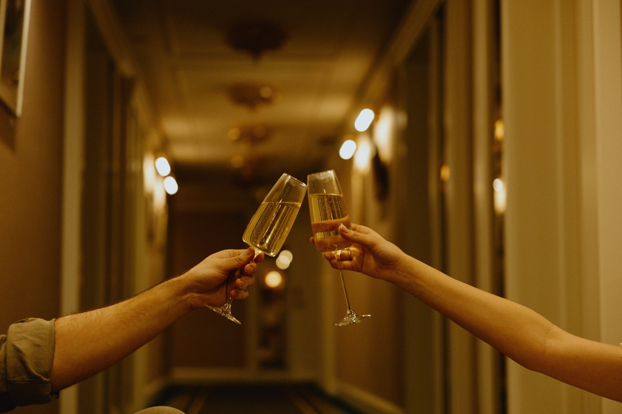 Руки жениха и невесты с бокалами.Невеста в свадебном платье с жемчужным ожерельем.