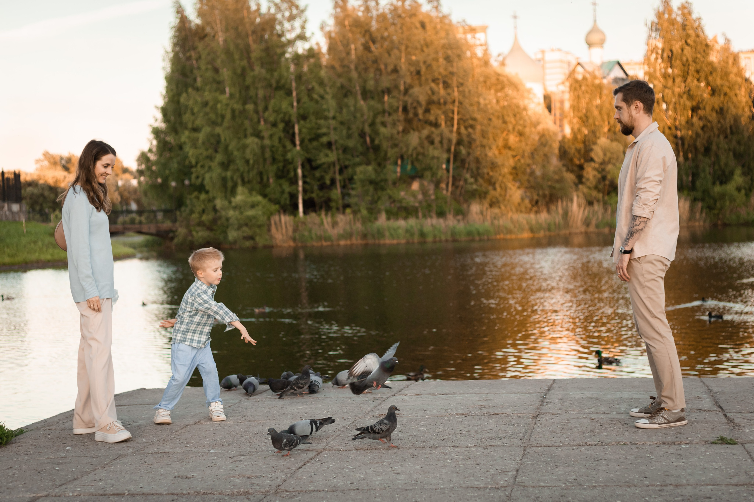 мама папа и сын кормят голубей на прогулке в парке