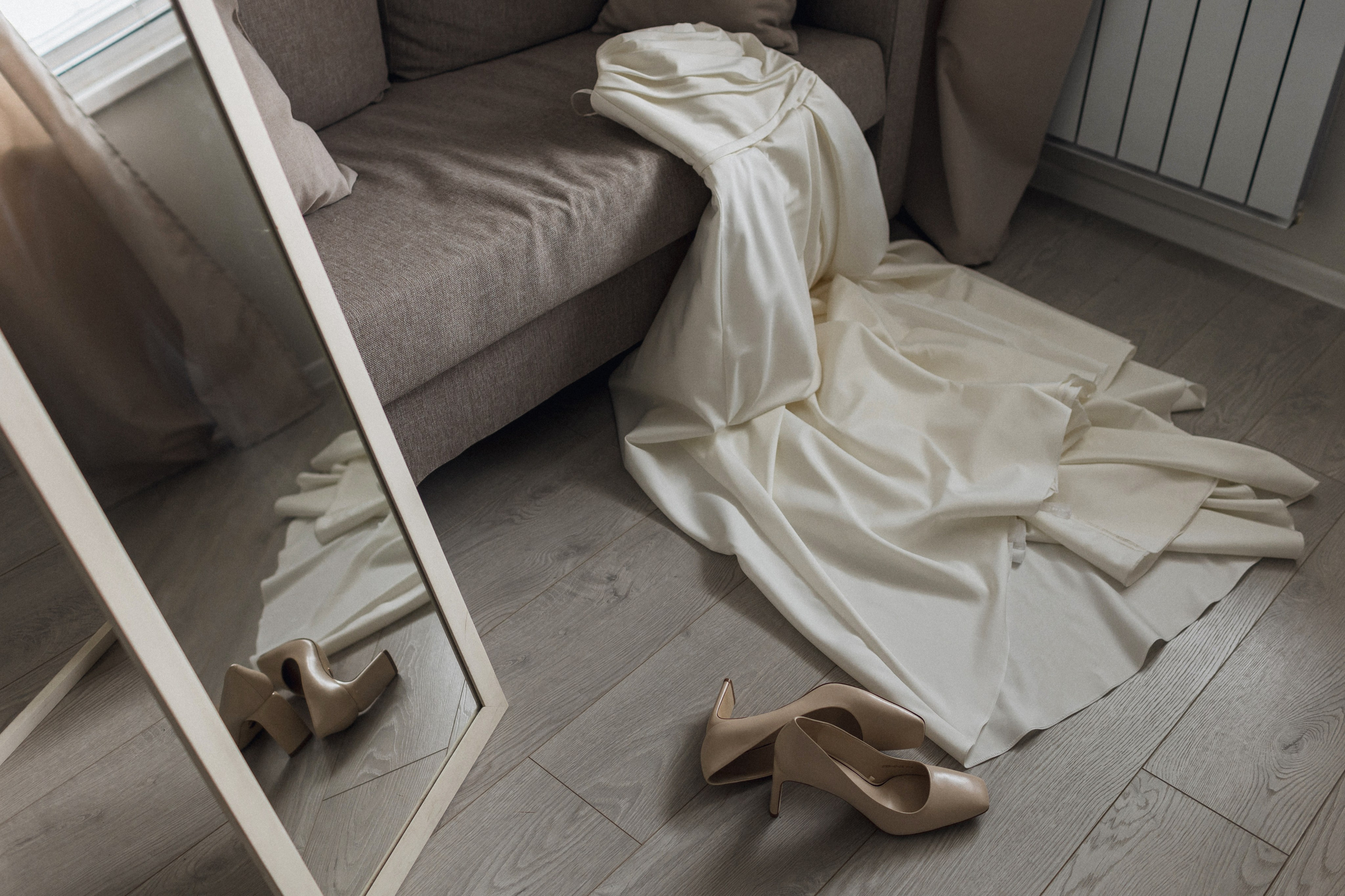 Свадебный лукбук в деталях: игра отражений платья и туфель на паркете с  диваном для концепции элегантной минималистичной съемки