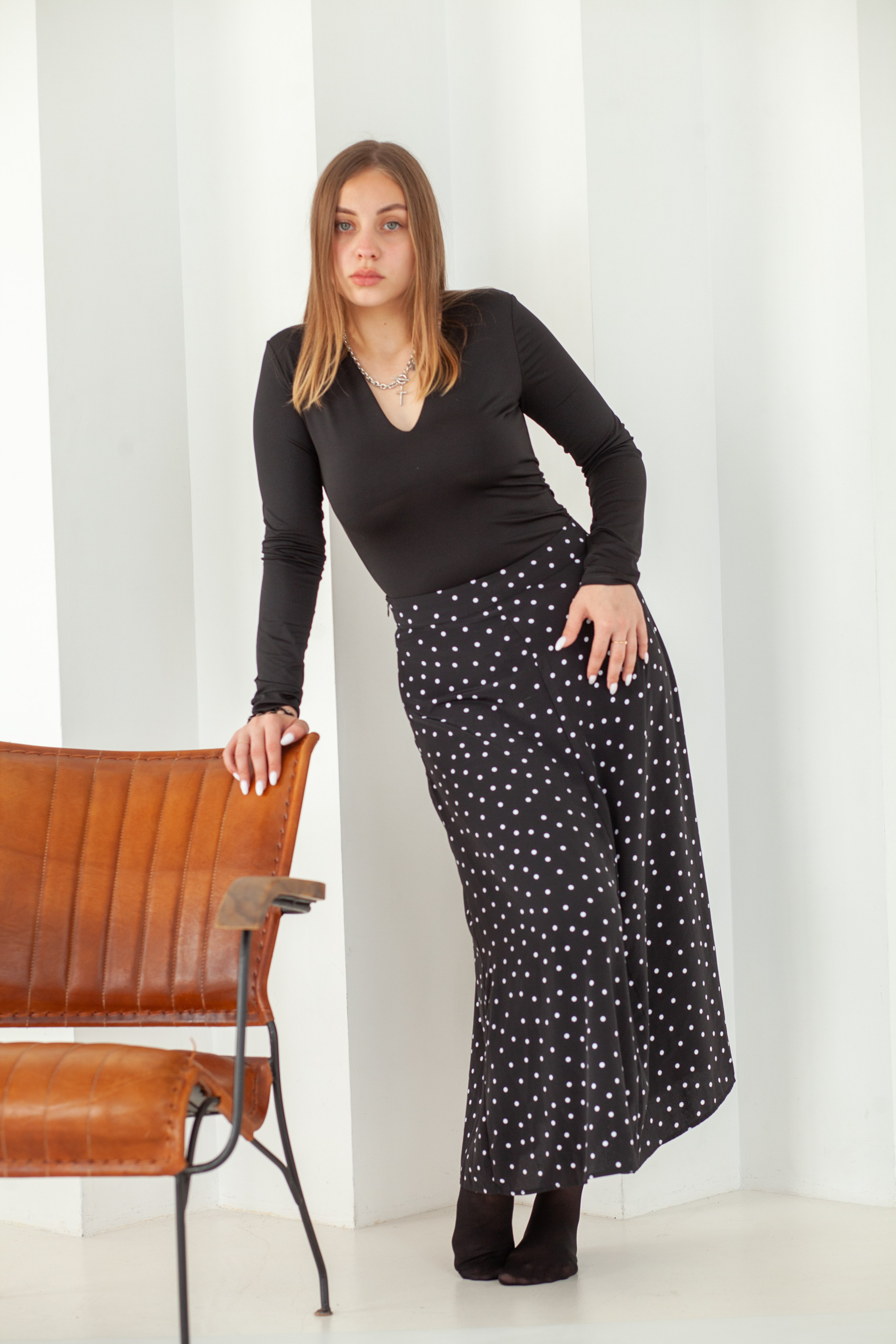 Девушка в тёмной одежде стоит рядом с креслом