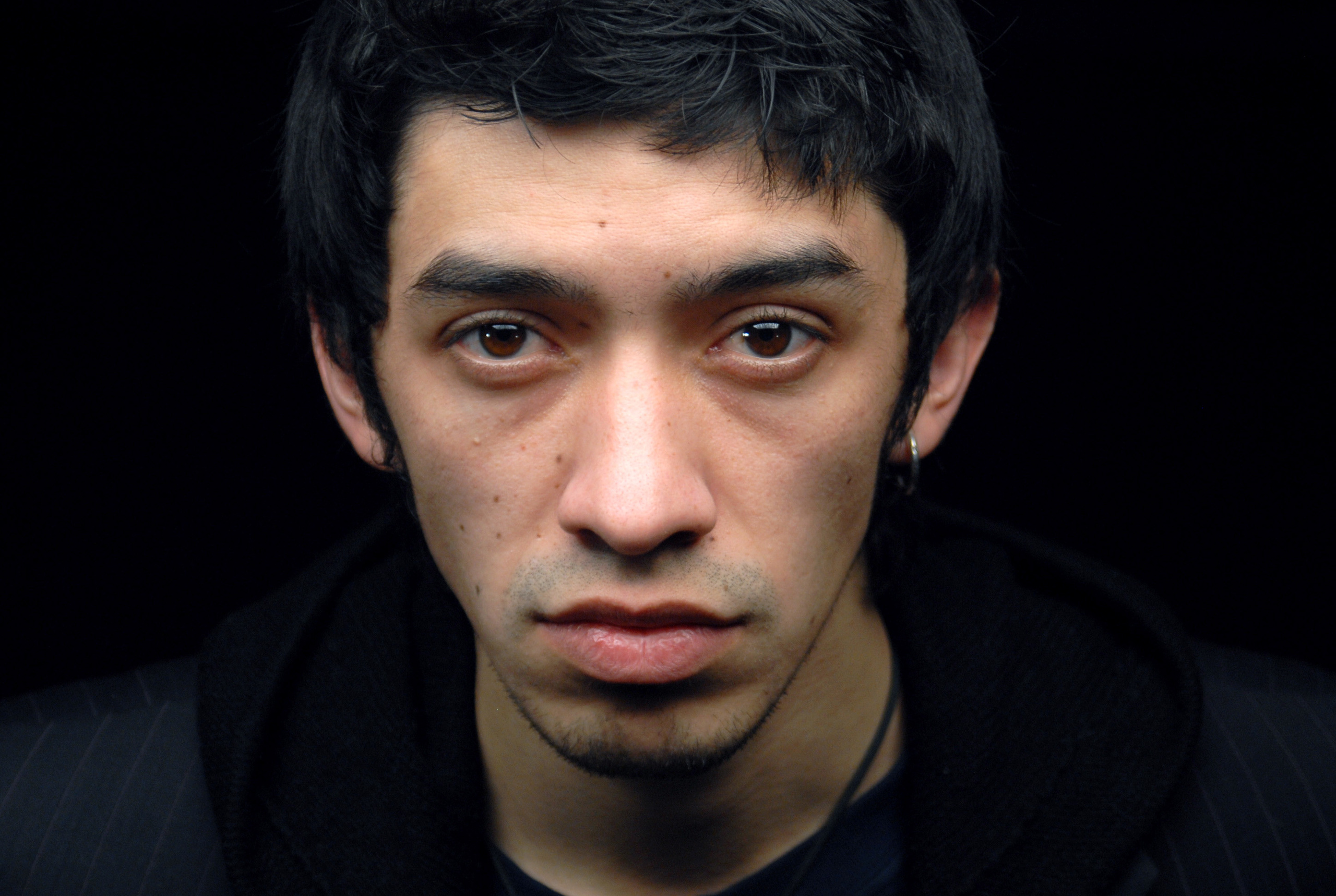 Портрет симпатичного юноши на черном фоне.