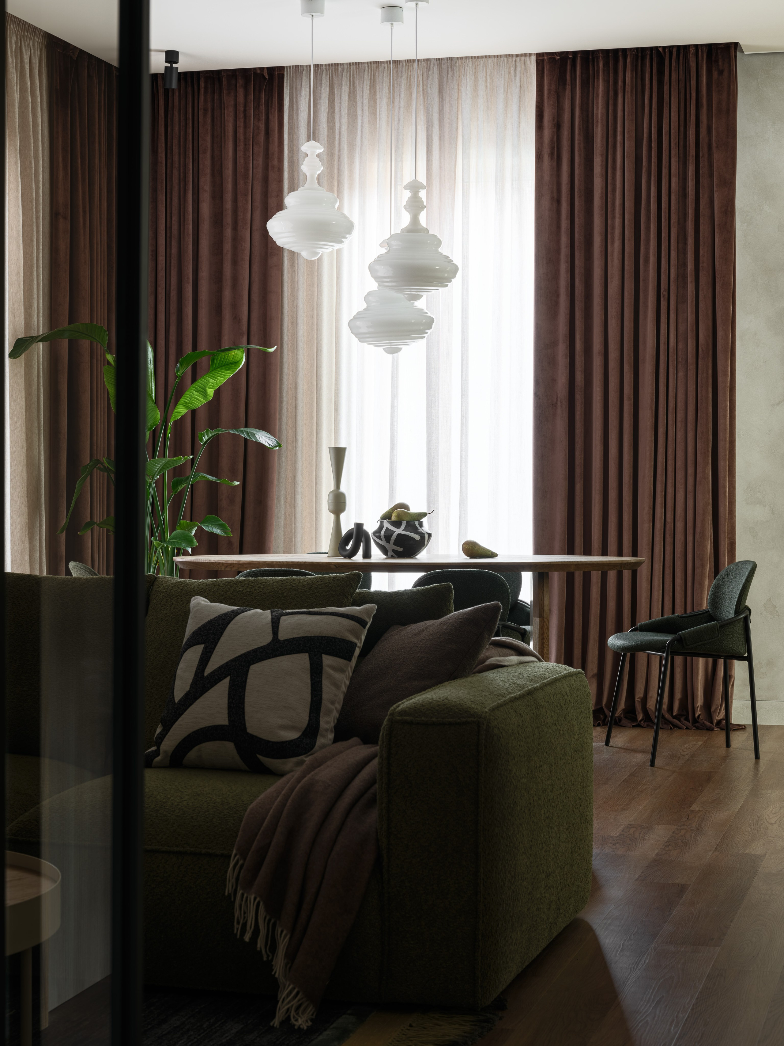 Общий вид гостиной и столовой с зелёным диваном и современной мебелью. Интерьер Наталии Шелепниковой, снятый Сергеем Денисенко и стилизованный Алёной Бершацкой, сочетает комфорт, натуральность и современный дизайн.